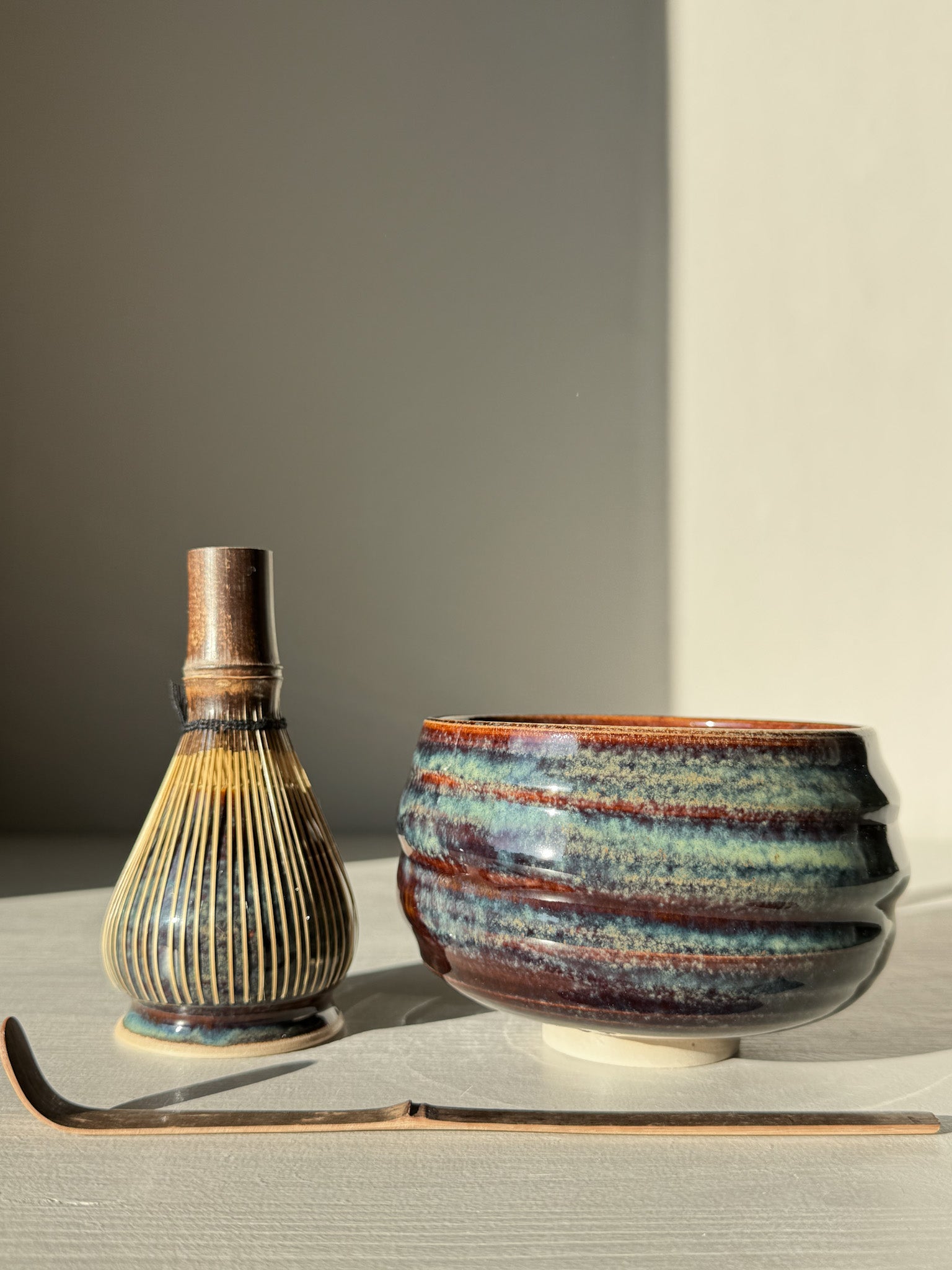 Matcha Bowl - Glossy Blue #03 with bamboo whisk and scoop, showcasing deep earthy tones and flowing blues with a raised foot design.