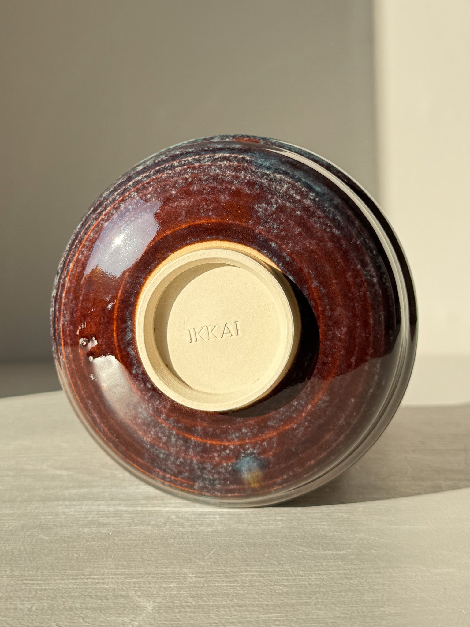 Bottom view of Matcha Bowl - Glossy Blue #03 with earthy tones and raised foot, showcasing unique flowing curves and soft texture.