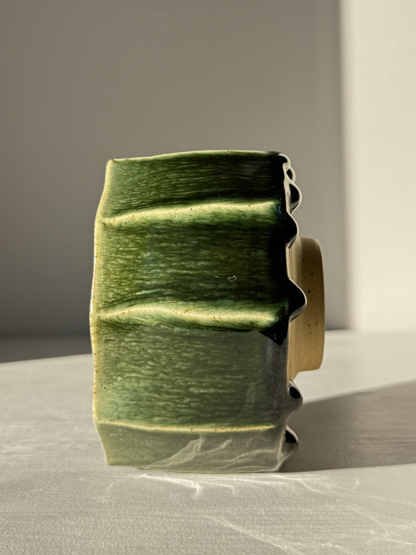 Side view of Faceted Matcha Bowl - Hinoki #01 with deep green glaze drips on hand-carved facets, showcasing its artistic craftsmanship.