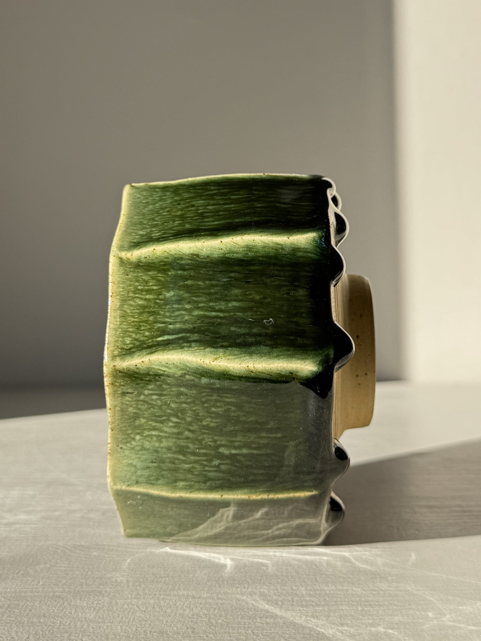 Side view of Faceted Matcha Bowl - Hinoki #01 with deep green glaze drips on hand-carved facets, showcasing its artistic craftsmanship.