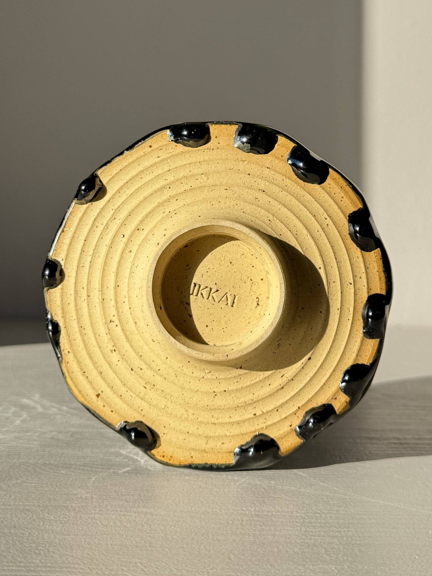 Base of Faceted Matcha Bowl - Hinoki #02 with kiln marks and hand-carved facets, featuring a deep green glaze on the rim.