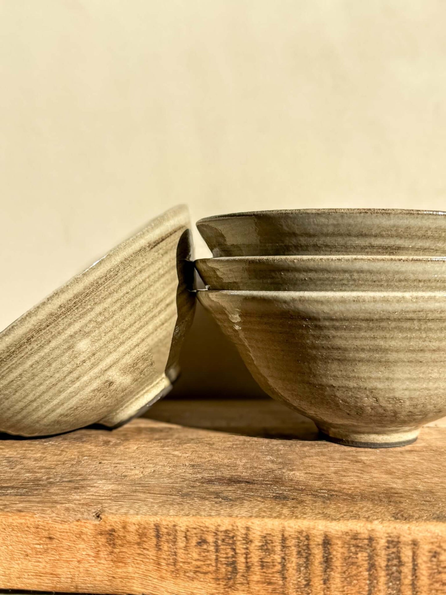 Stacked Yuki Series dark clay bowls with soft white glaze on wooden surface