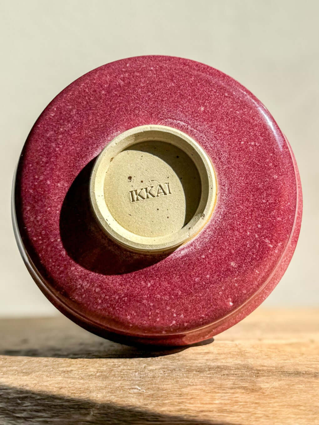 Bottom view of Matcha Bowl - Ume Series #04 showing unique speckled glaze and trimmed foot resting on wooden surface.