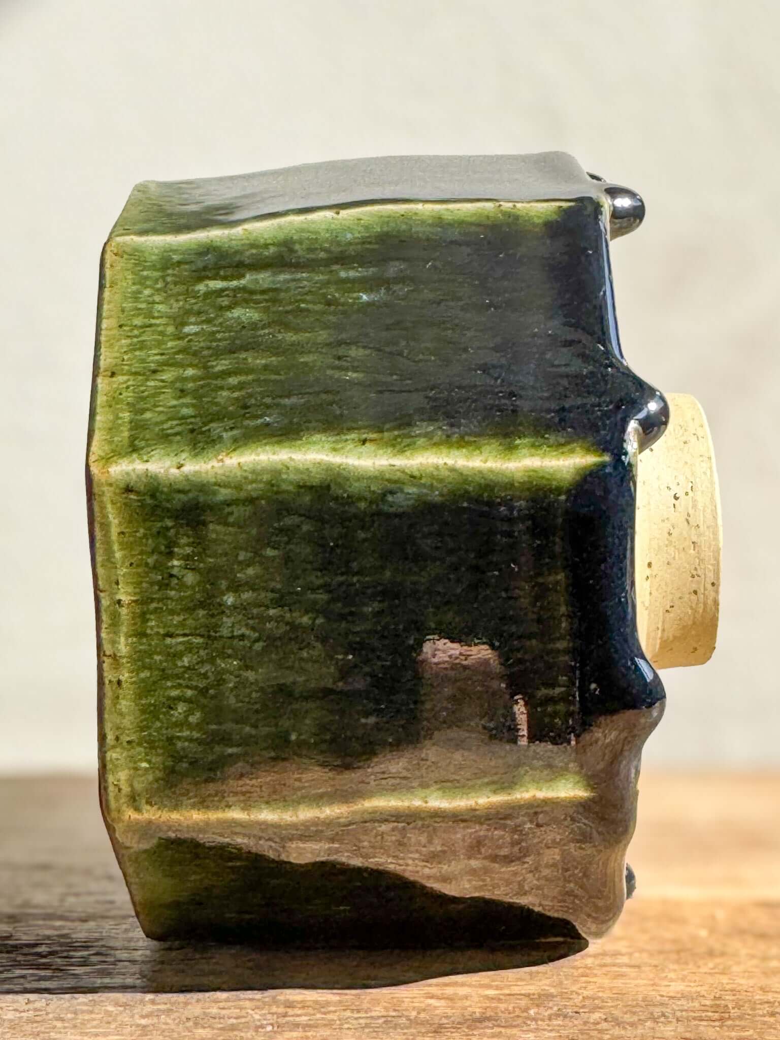 Faceted matcha bowl with deep green glaze from Hinoki Series, showing handmade carved lines and light-reflecting facets.