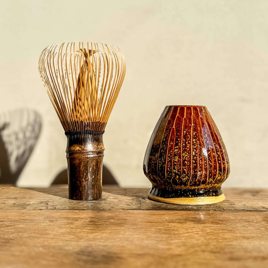 Matcha whisk and Kinsei Carved holder with amber glaze for optimal drying and aesthetics on a wooden surface.