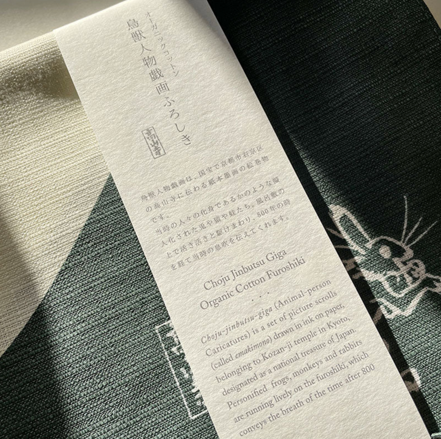 Close-up of woven organic cotton texture and product label on green Japanese medium furoshiki cloth.