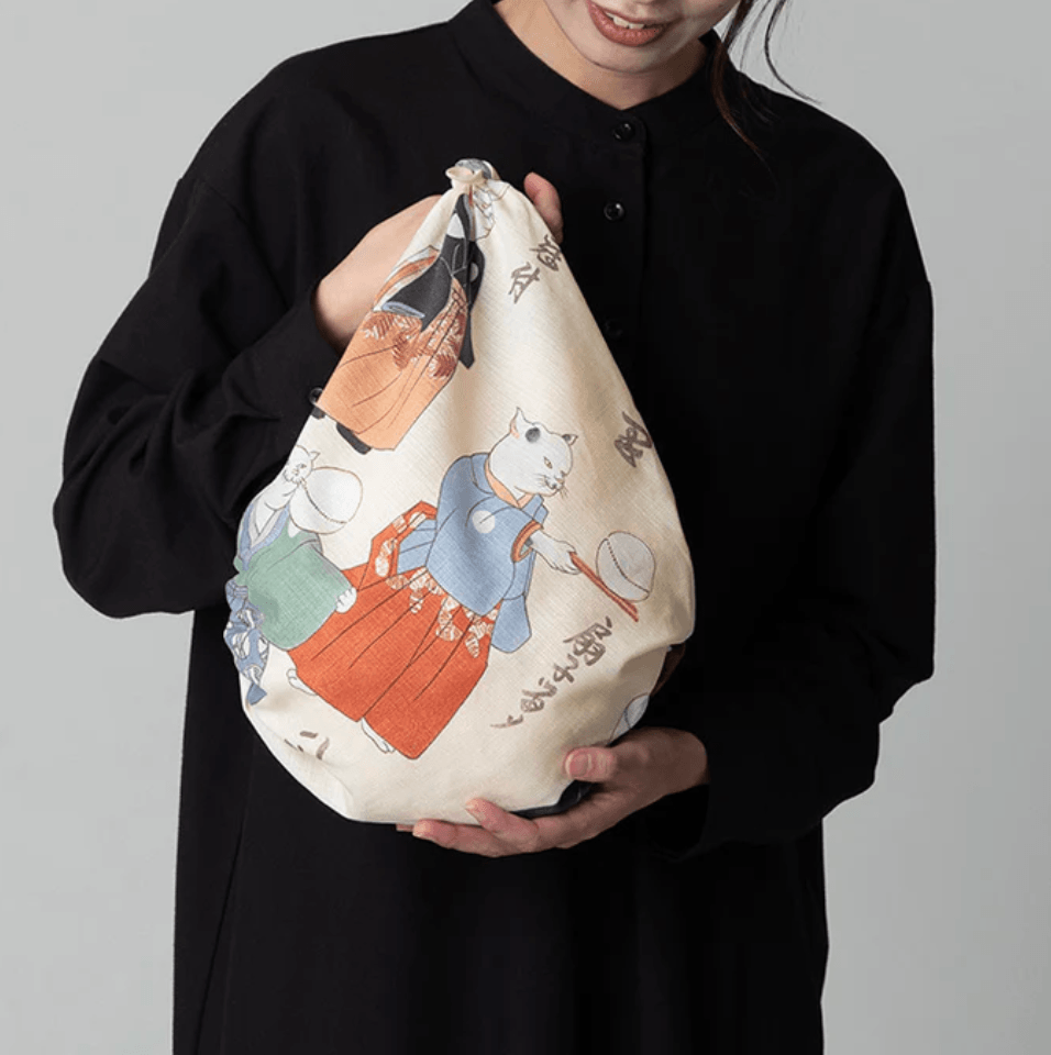 Medium Furoshiki Cats Juggling Balls Pattern bag held by a woman in a black outfit, showcasing traditional designs.