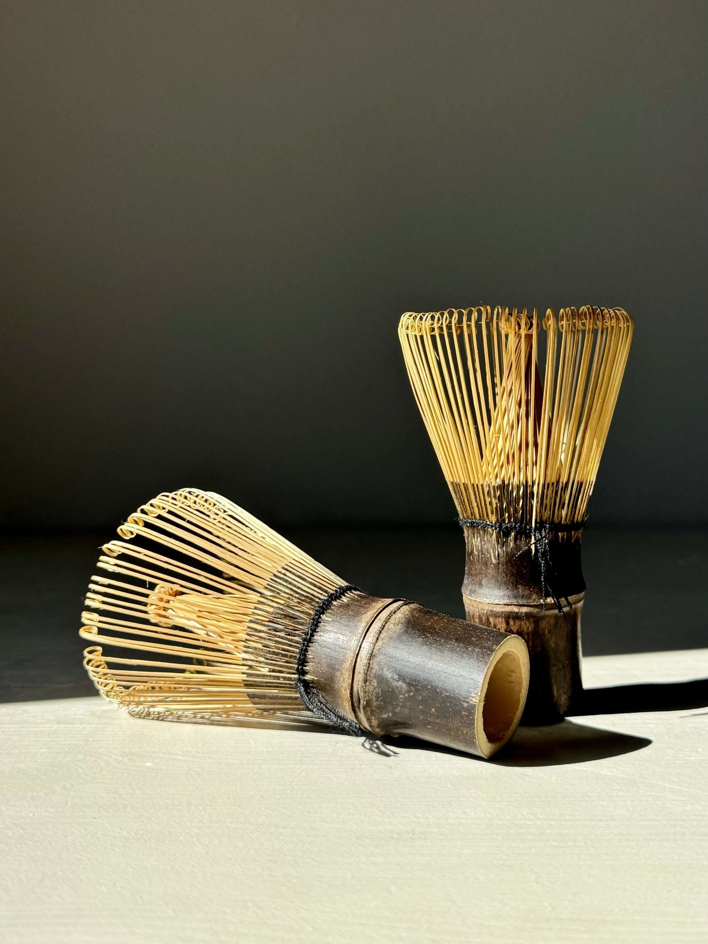 Dark brown bamboo matcha whisks (Chasen) on a light surface, showcasing natural elegance and craftsmanship for traditional tea rituals.