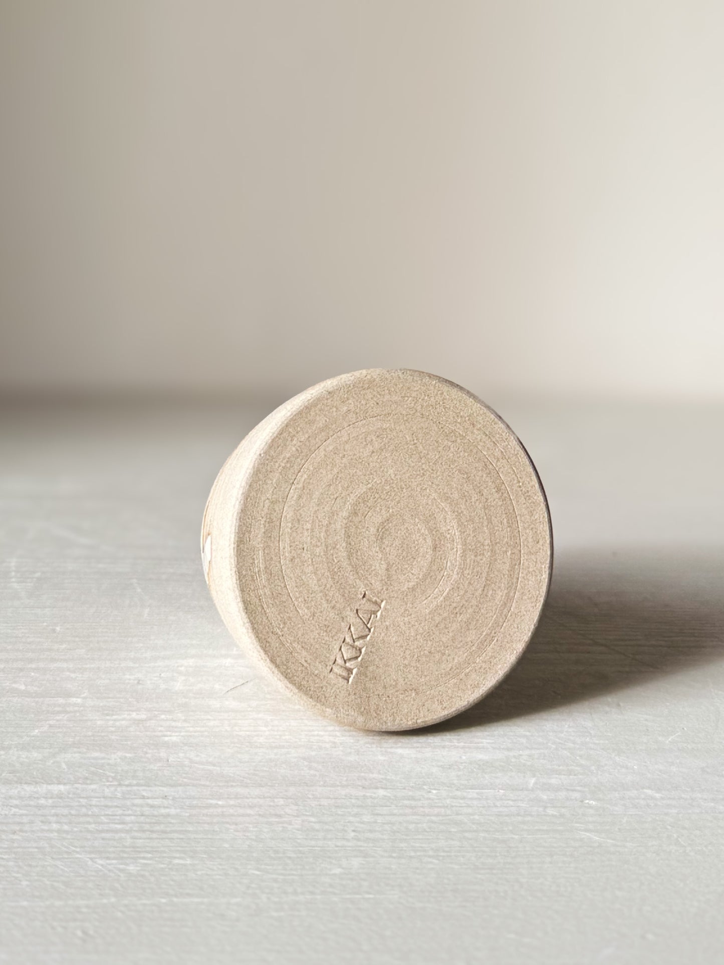 Bottom view of Small Vase – Yuki #01 with matte raw clay base and subtle circular patterns on a light surface.