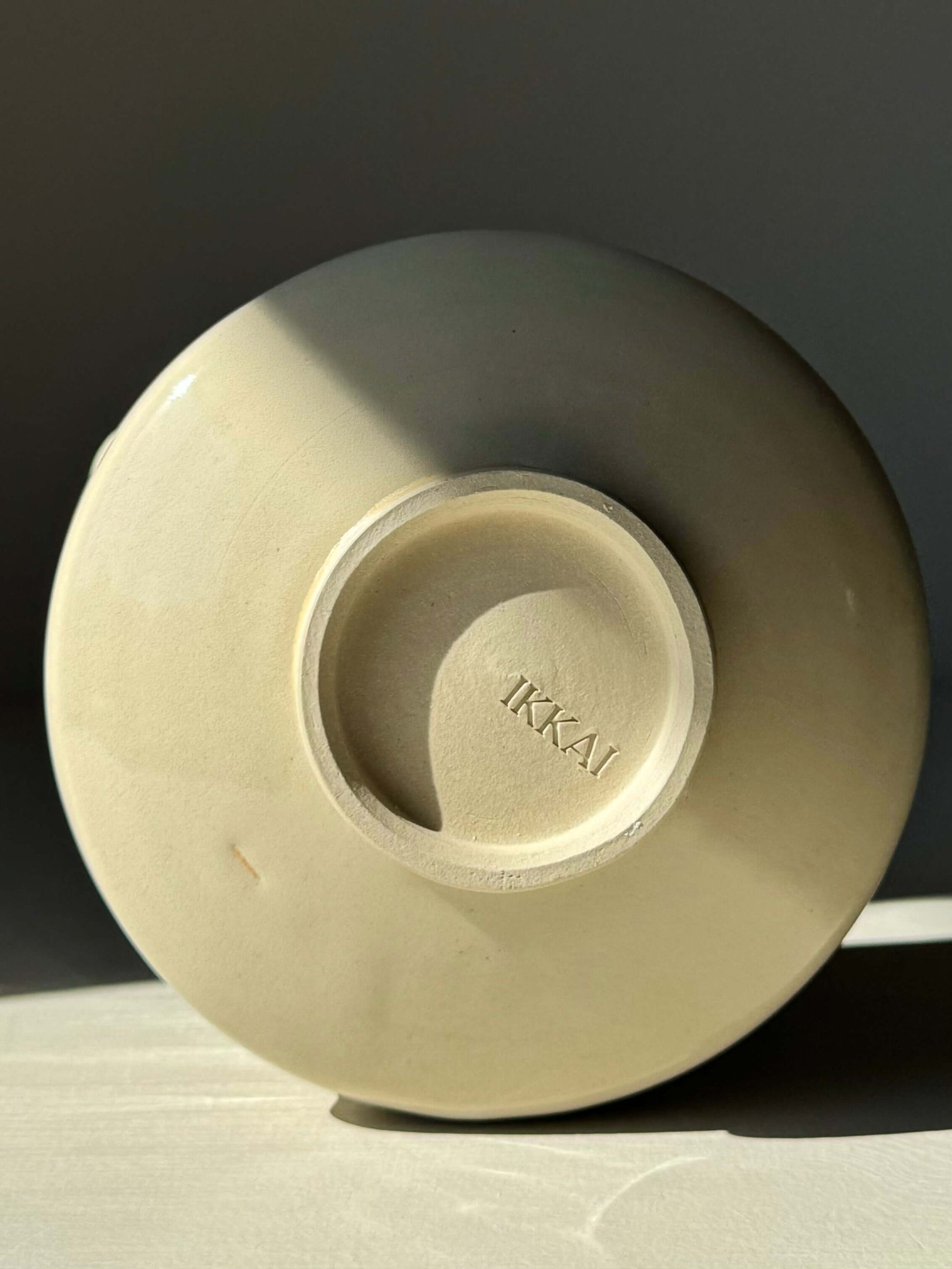 Bottom view of a ceramic matcha bowl with 'IKKAI' imprint, showcasing its clear glaze finish and subtle ridges.