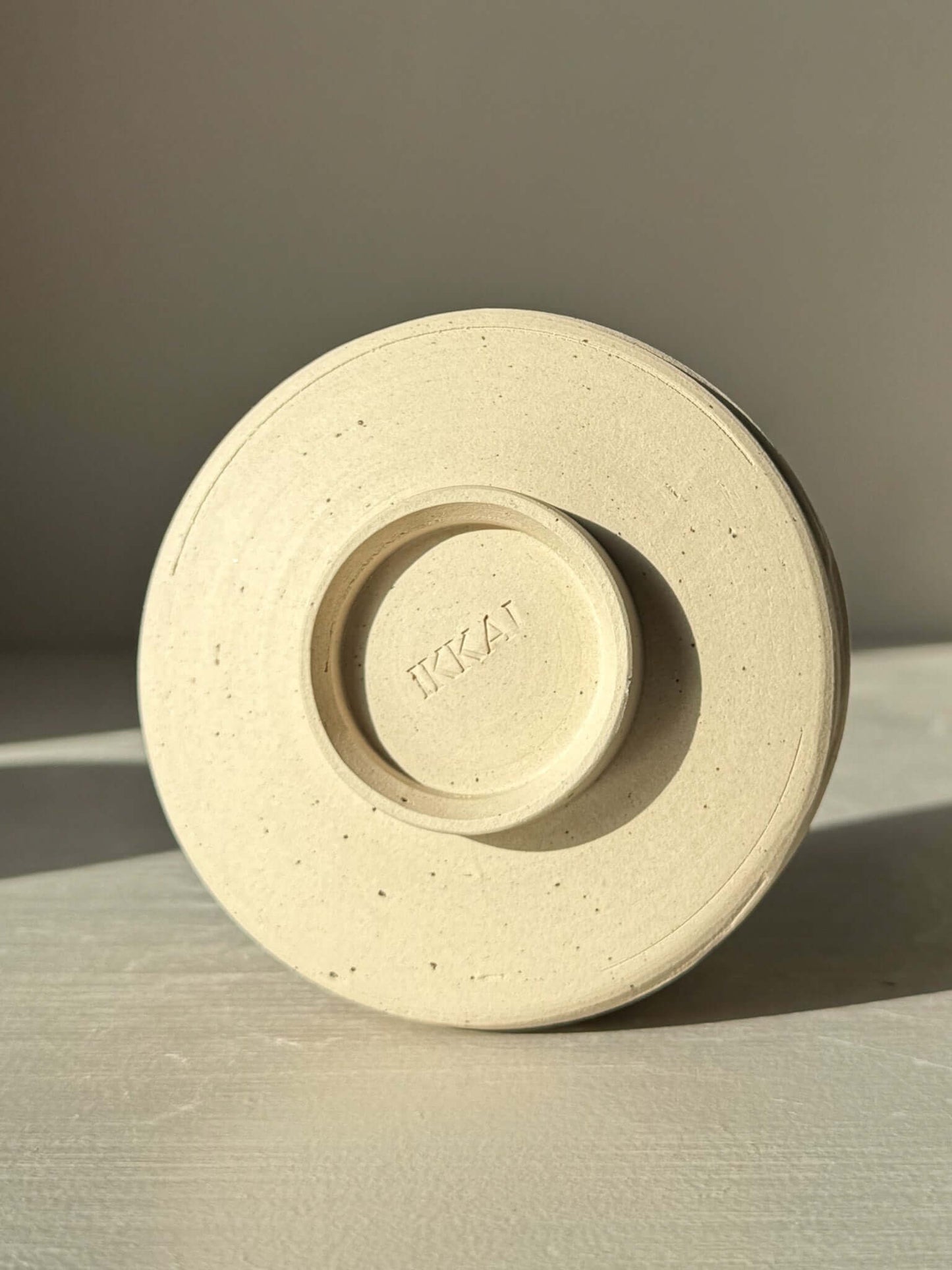 Bottom view of Yunomi Cup – Glossy White #02 showcasing branding and stoneware texture.