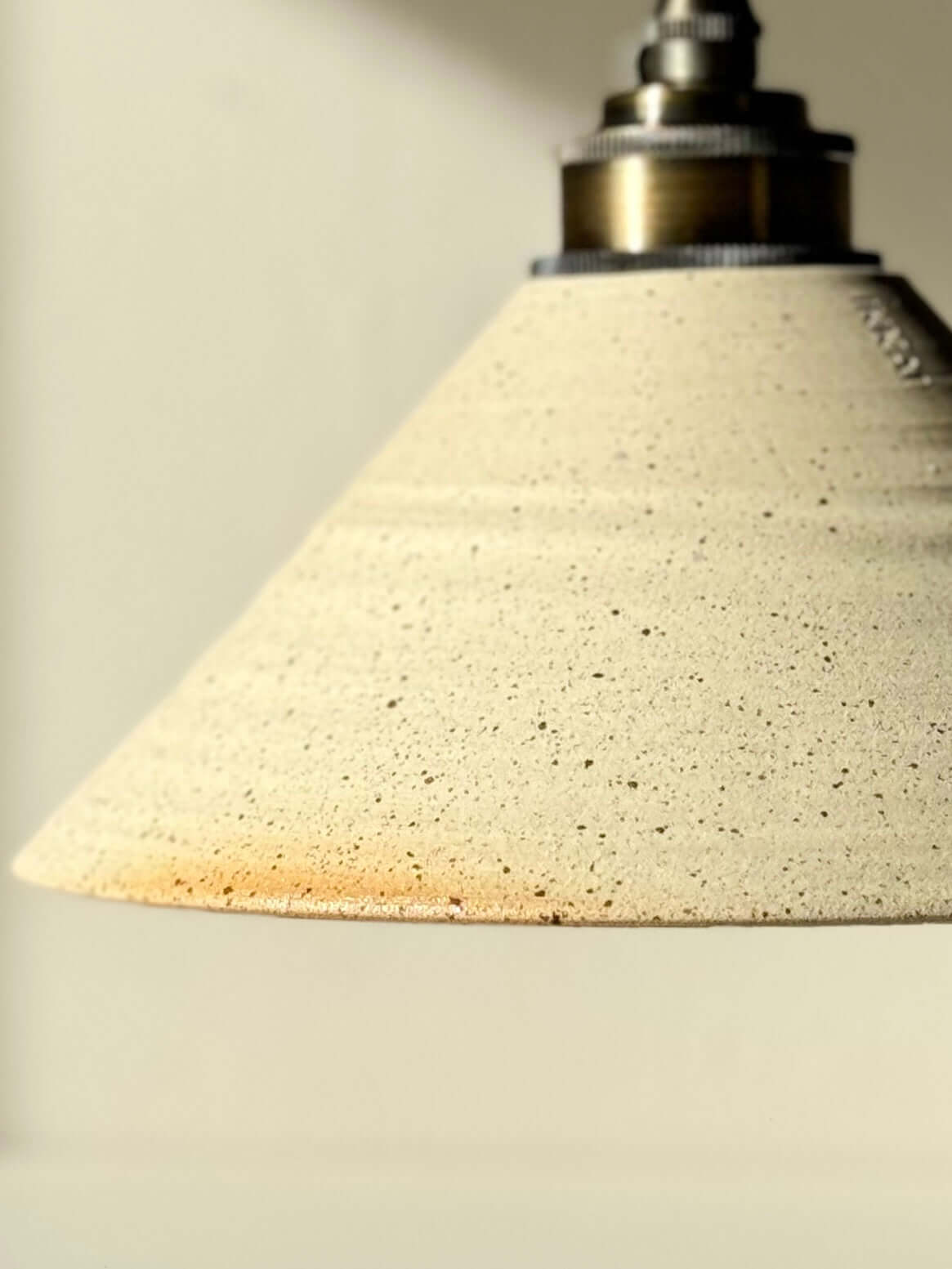 Ceramic lamp shade with unglazed texture and clear glazed interior, creating a warm, inviting glow in any space.