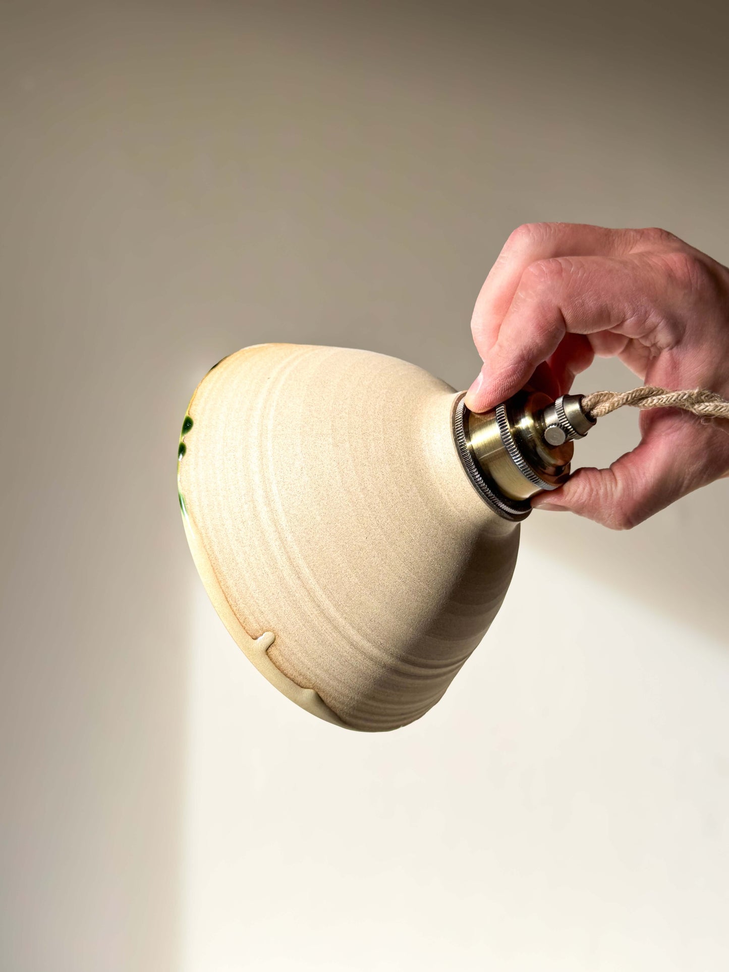 Hand holding Ceramic Lamp Shade – Mori #01 with forest green glaze and raw texture, showcasing handmade ceramic craftsmanship.