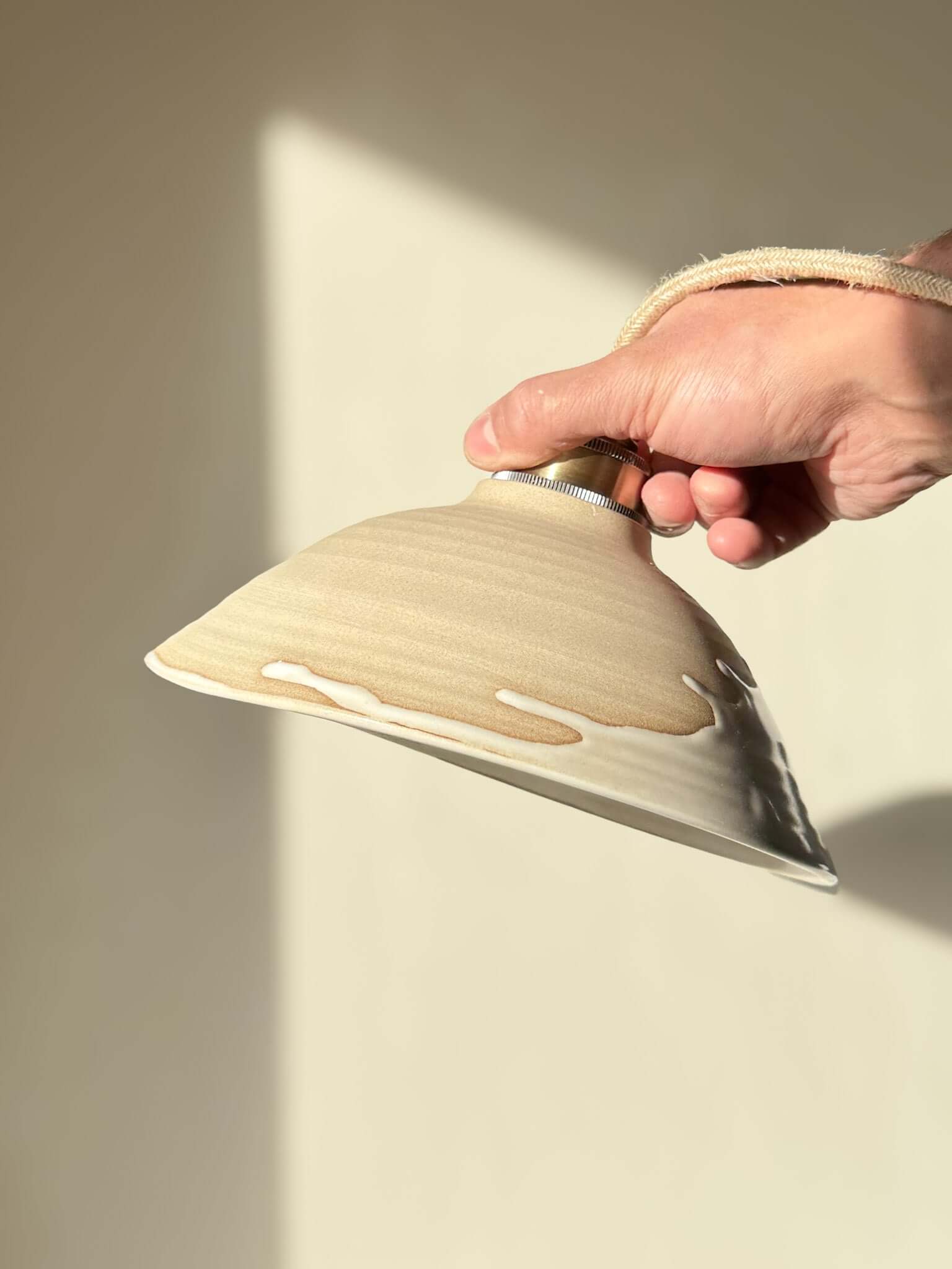 Hand holding Ceramic Lamp Shade – Yuki #02 with glossy white glaze and warm raw clay finish, showcasing a soft, elegant design.