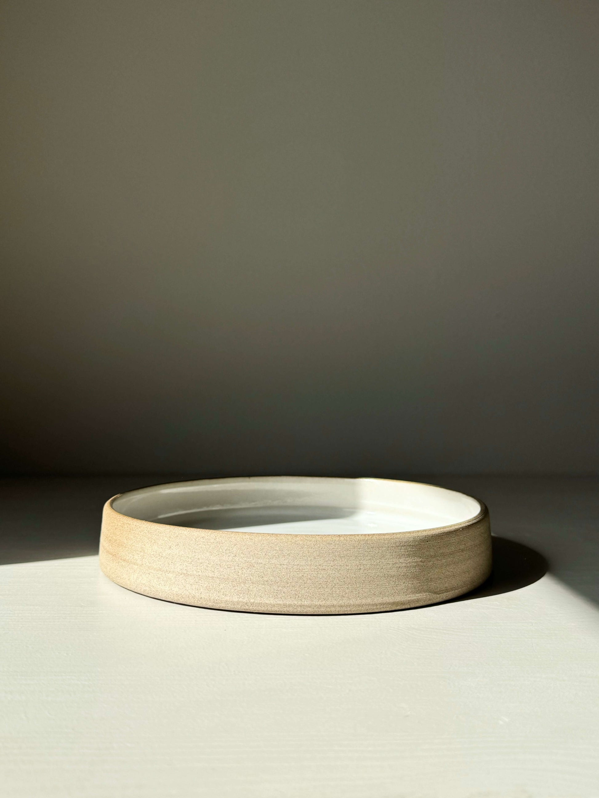Ceramic plate from the Yuki Series with a glossy white glaze and toffee-colored clay, low shape with a gentle curve.