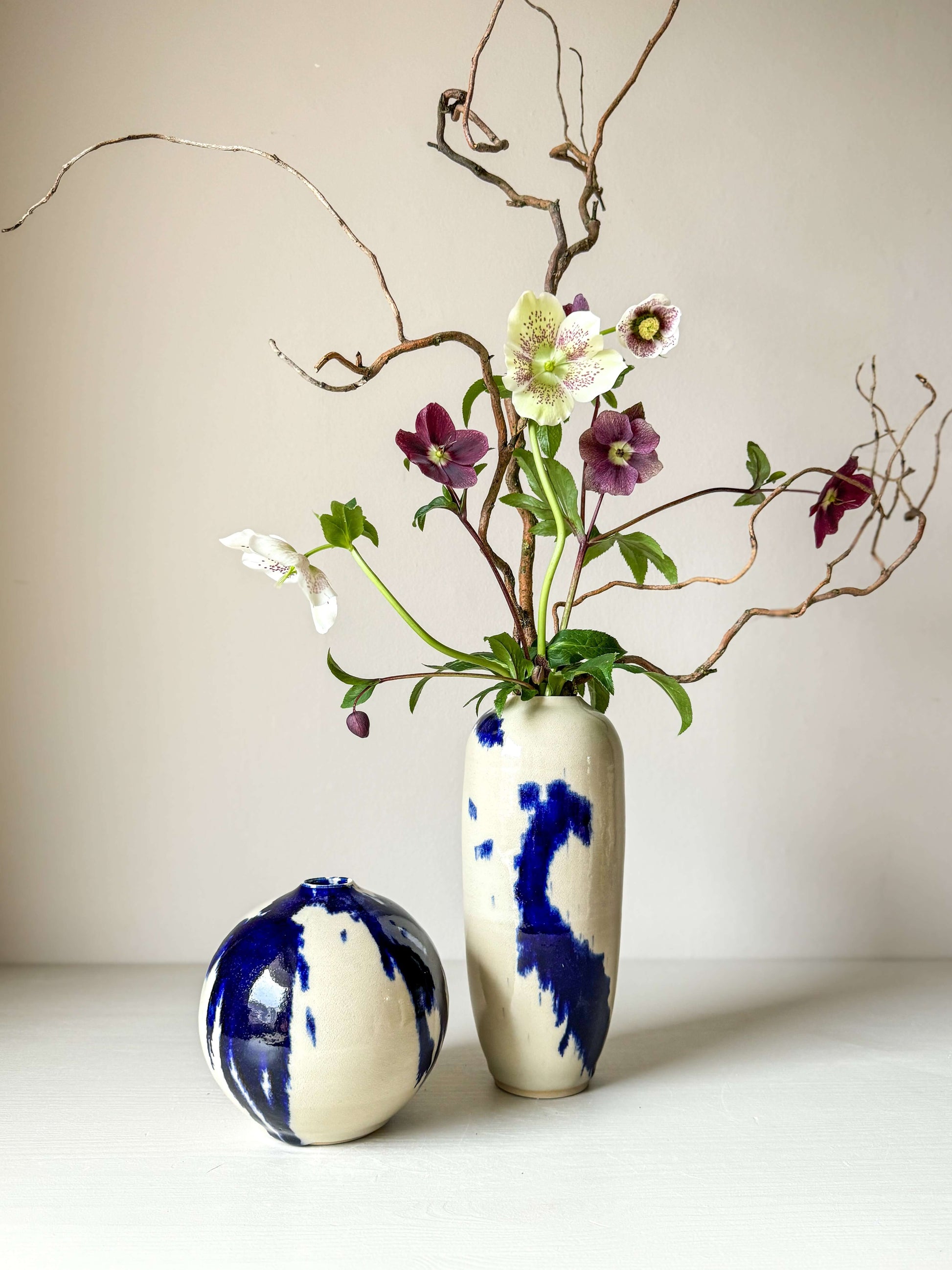 Ceramic vase from Gosu Series with hand-splashed cobalt blue accents and glossy clear glaze, featuring unique design and flowers.
