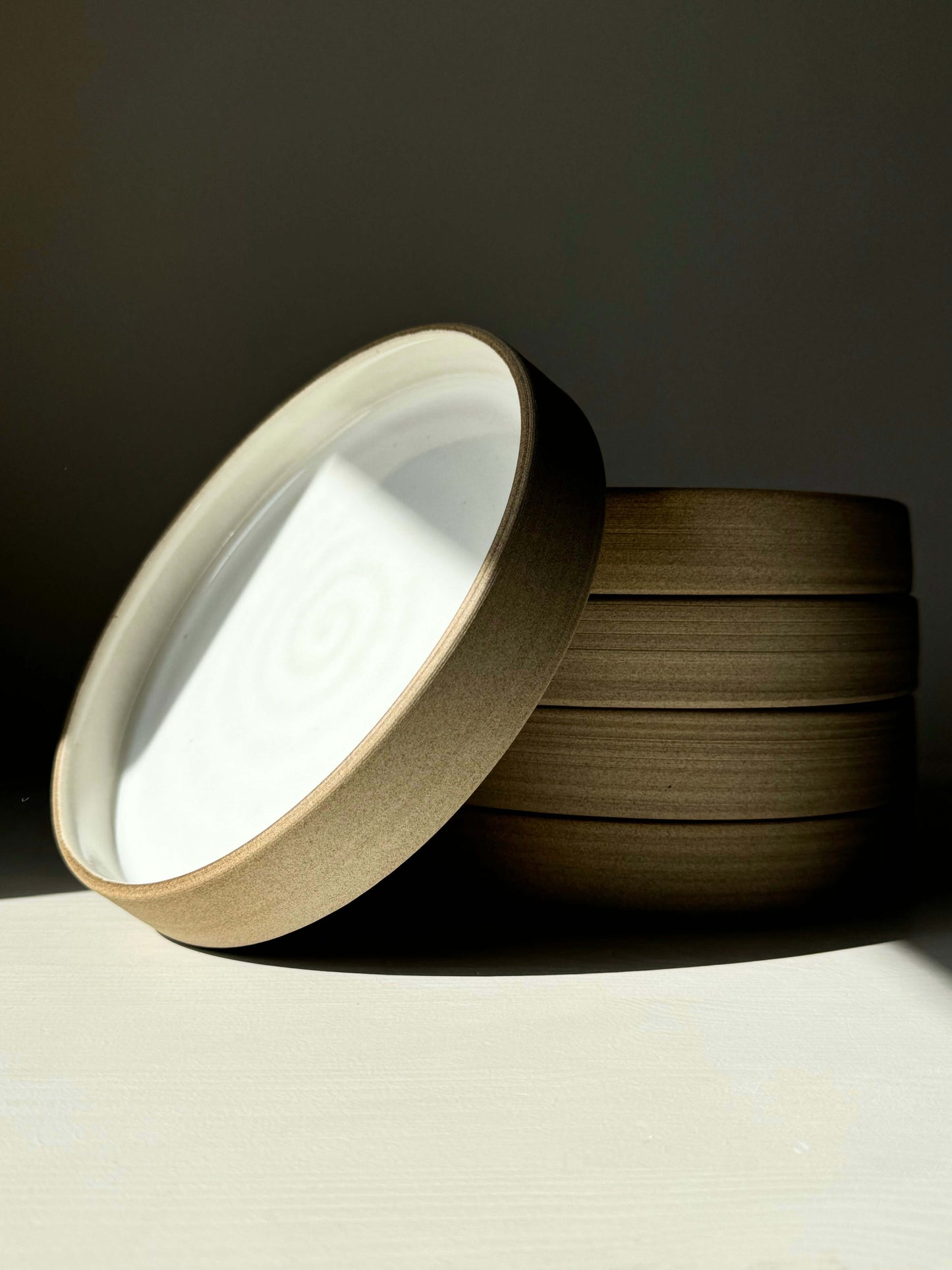 Stacked ceramic plates from Yuki Series, featuring glossy white glaze inside and matte toffee exterior; calm and warm design.