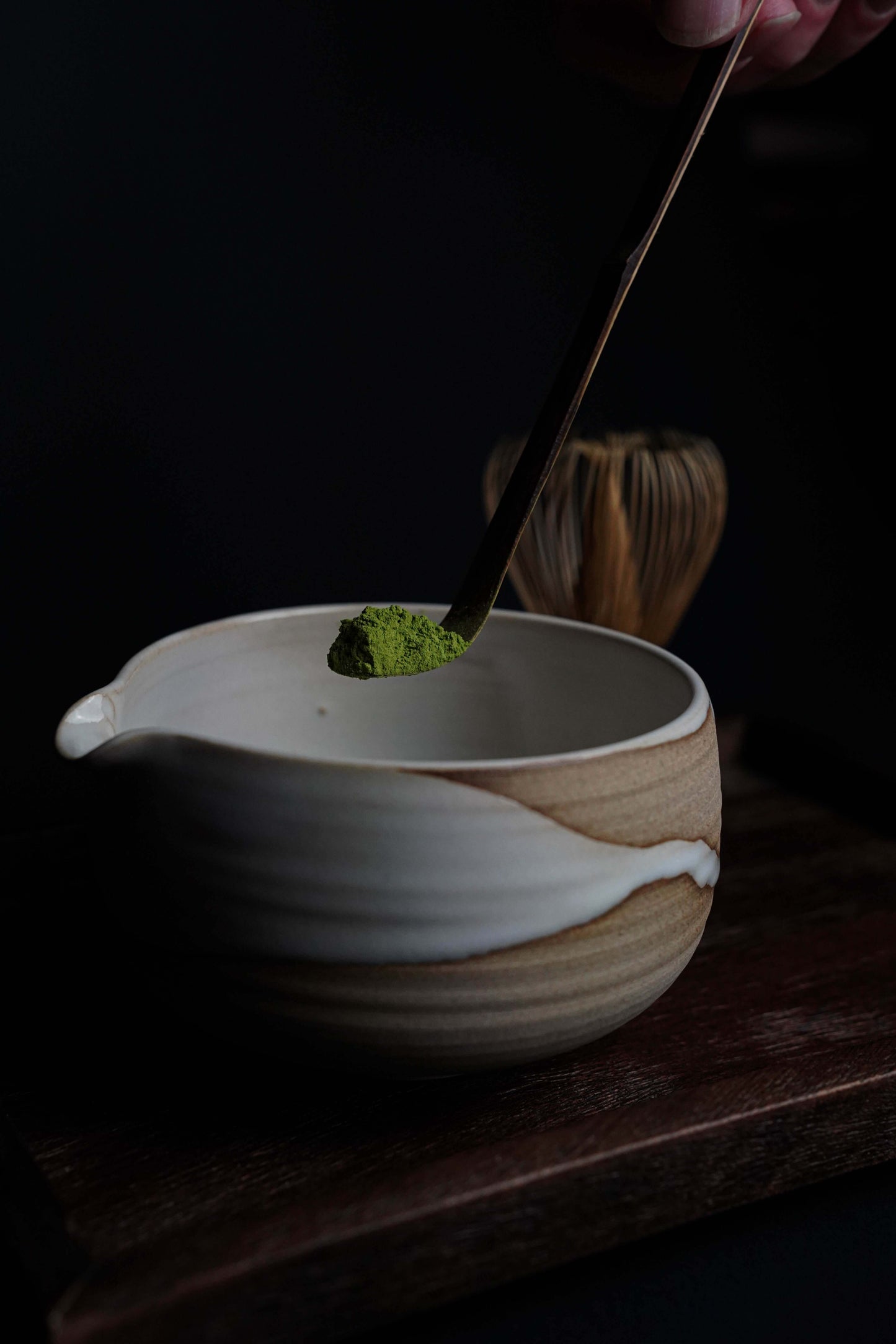 Scooping Fuji Matcha – Japan (Ceremonial Grade) into a traditional bowl with bamboo whisk, showcasing vibrant green matcha powder.
