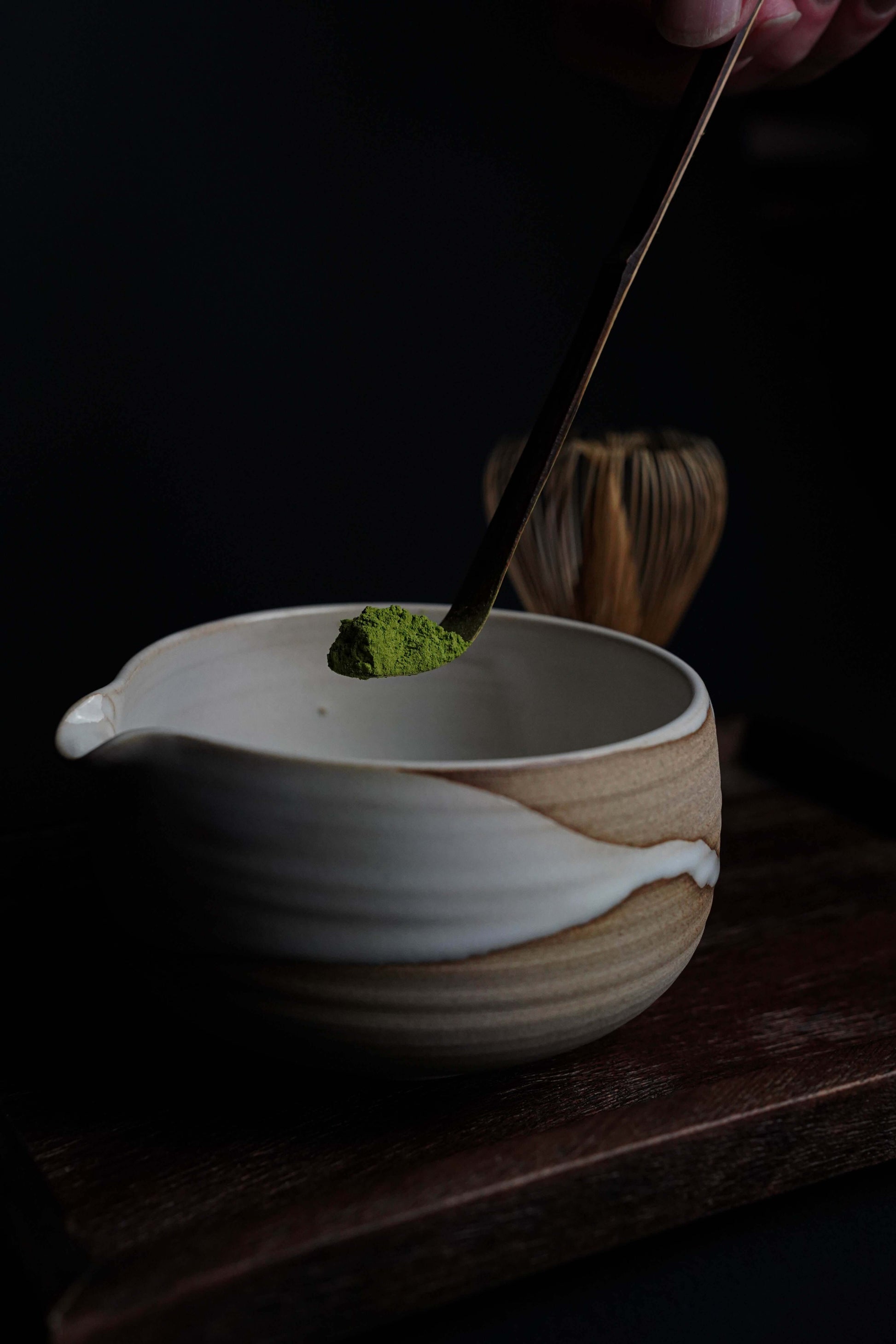 Scooping Fuji Matcha – Japan (Ceremonial Grade) into a traditional bowl with bamboo whisk, showcasing vibrant green matcha powder.