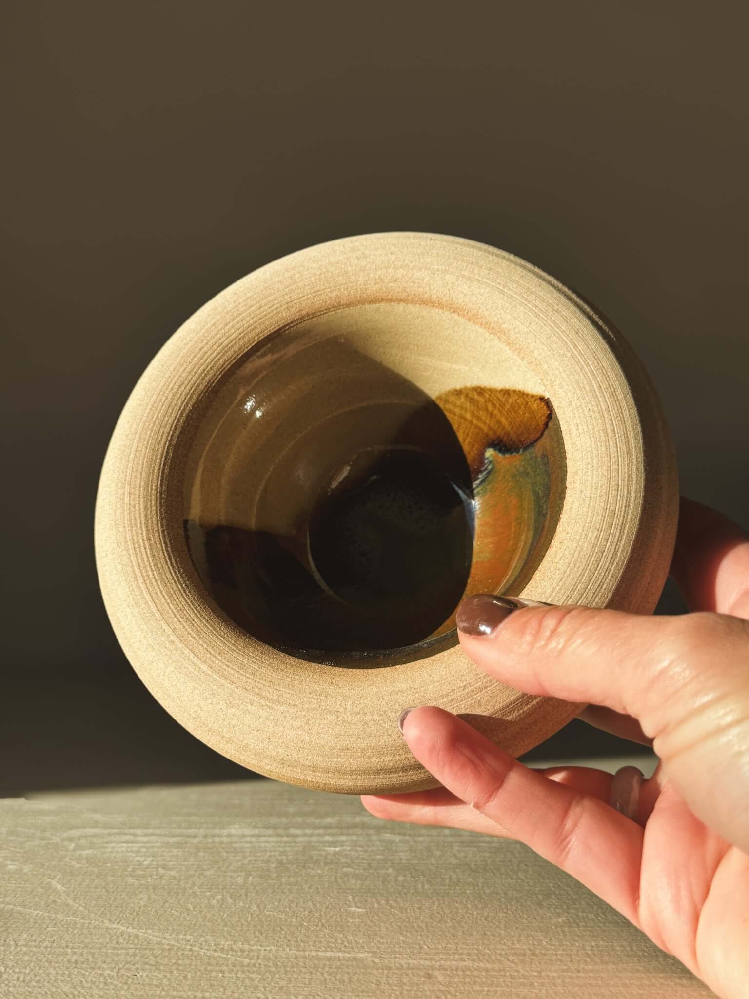 Double-Walled Bowl - Inyo #02 with soft toffee-toned clay exterior and rich brown, gold, blue glazes inside, held by a hand.