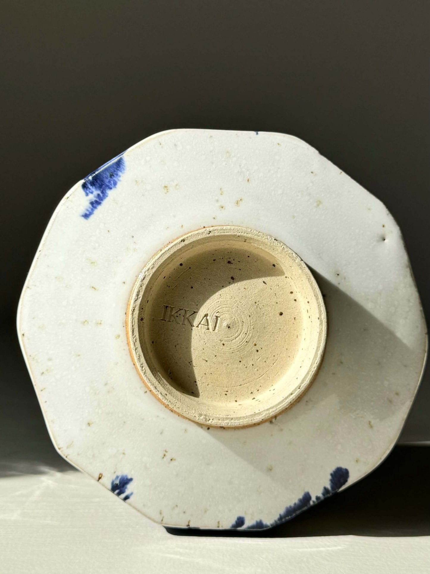 Bottom view of faceted matcha bowl with cobalt blue splashes and glossy white glaze, showcasing the handcrafted design.