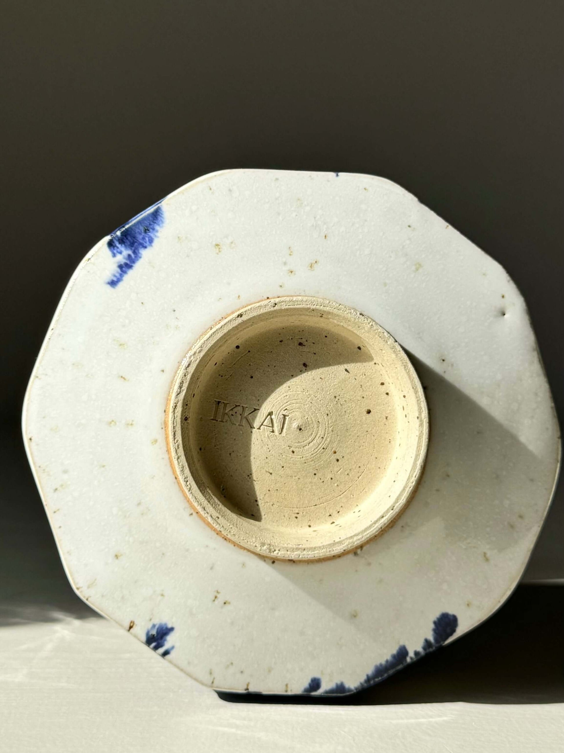Bottom view of faceted matcha bowl with cobalt blue splashes and glossy white glaze, showcasing the handcrafted design.