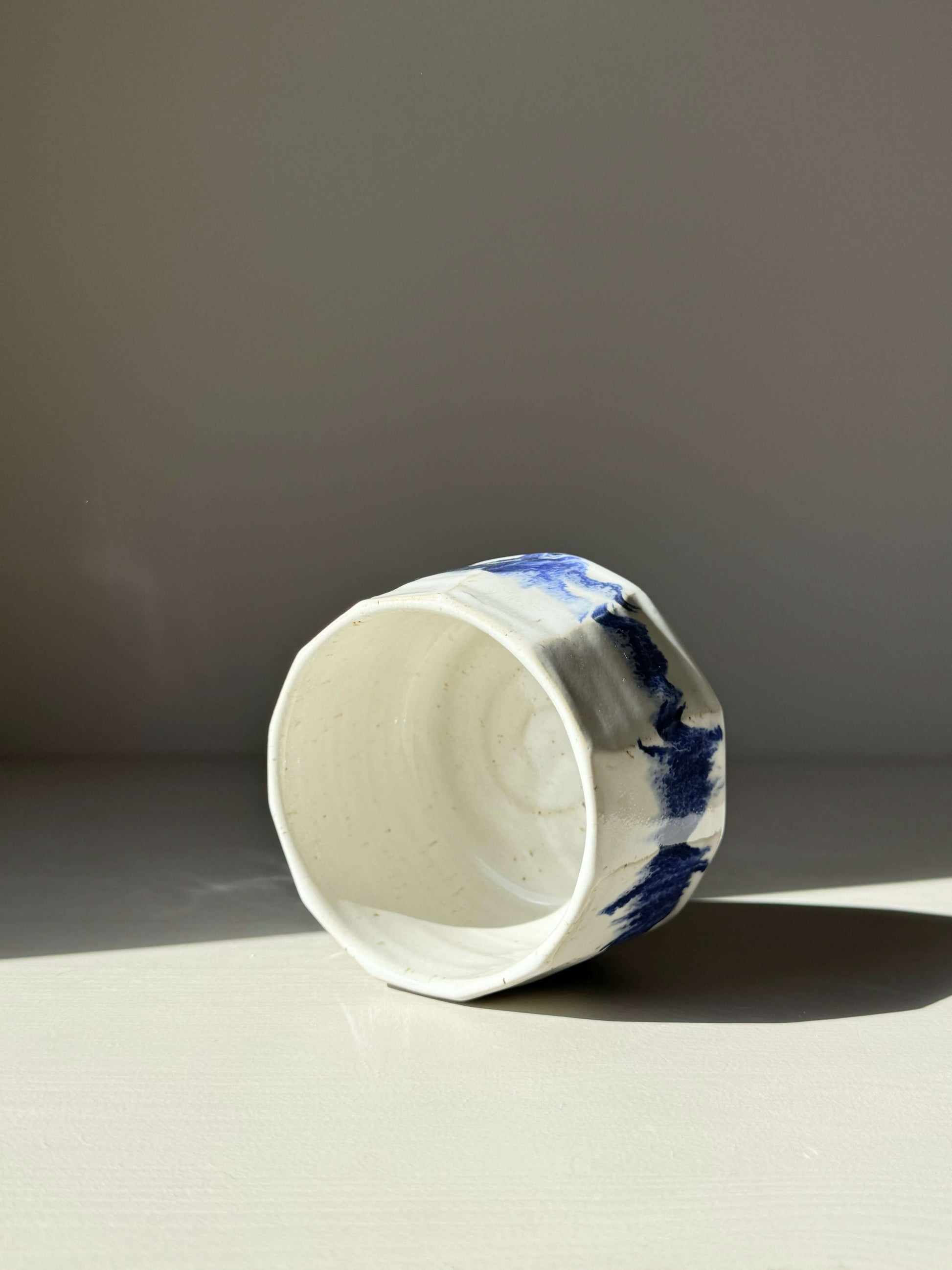 Faceted matcha bowl with cobalt blue accents and glossy white glaze, showcasing a striking modern design.