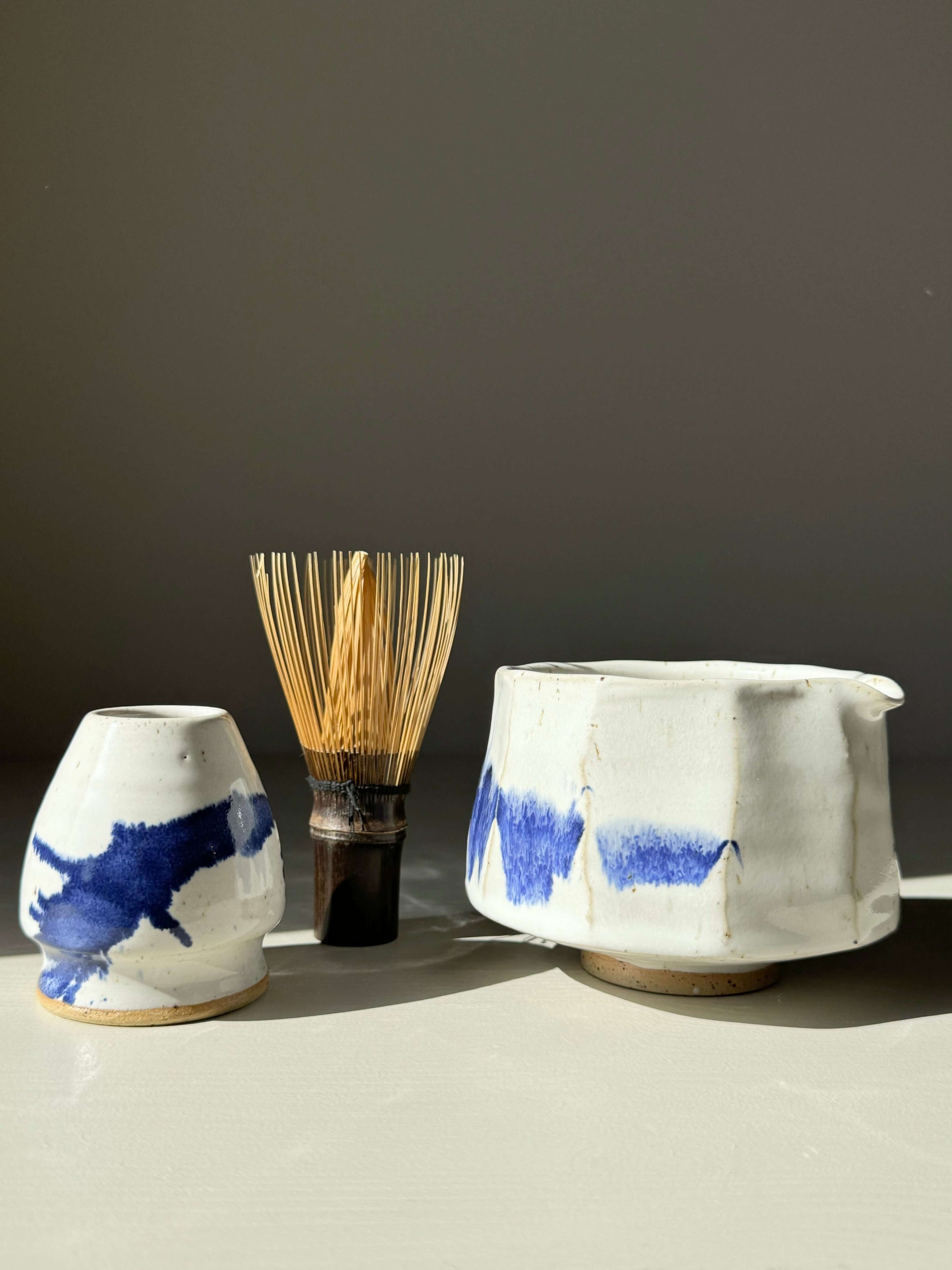 Faceted Matcha Bowl with Spout in glossy white glaze, cobalt blue splashes, paired with bamboo whisk, modern ceramic design