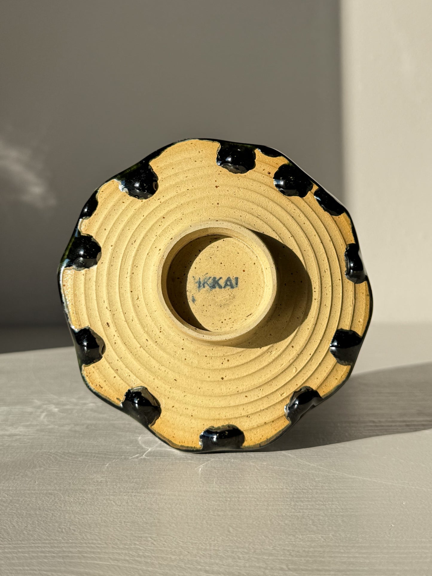 Bottom view of Faceted Matcha Bowl - Hinoki #03 showcasing unique black glaze drips and HIKAI signature on base.