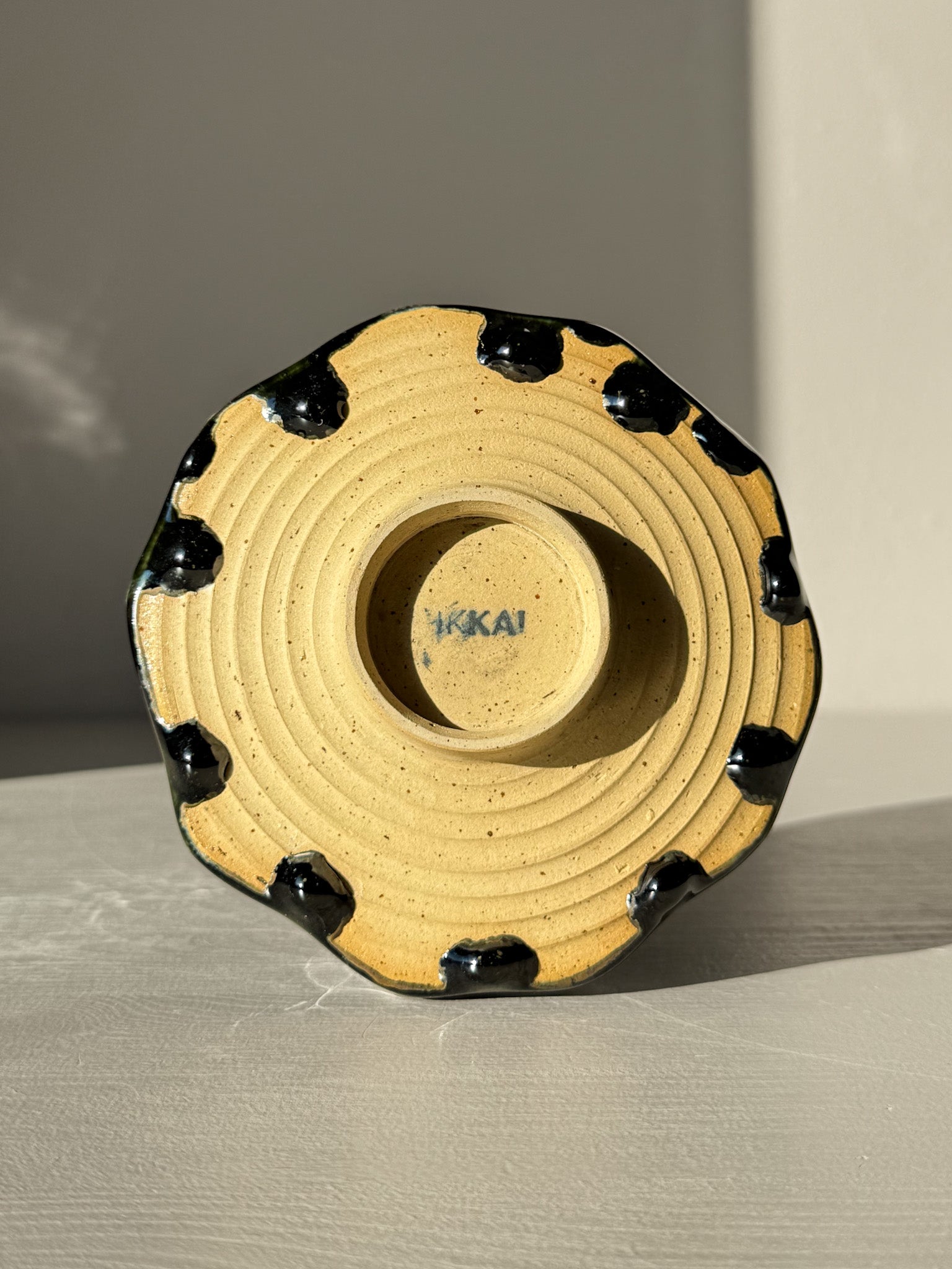 Bottom view of Faceted Matcha Bowl - Hinoki #03 showcasing unique black glaze drips and HIKAI signature on base.