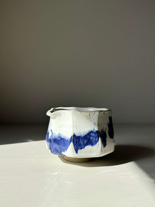 Faceted matcha bowl with spout featuring cobalt blue accents and glossy white glaze on a neutral background.
