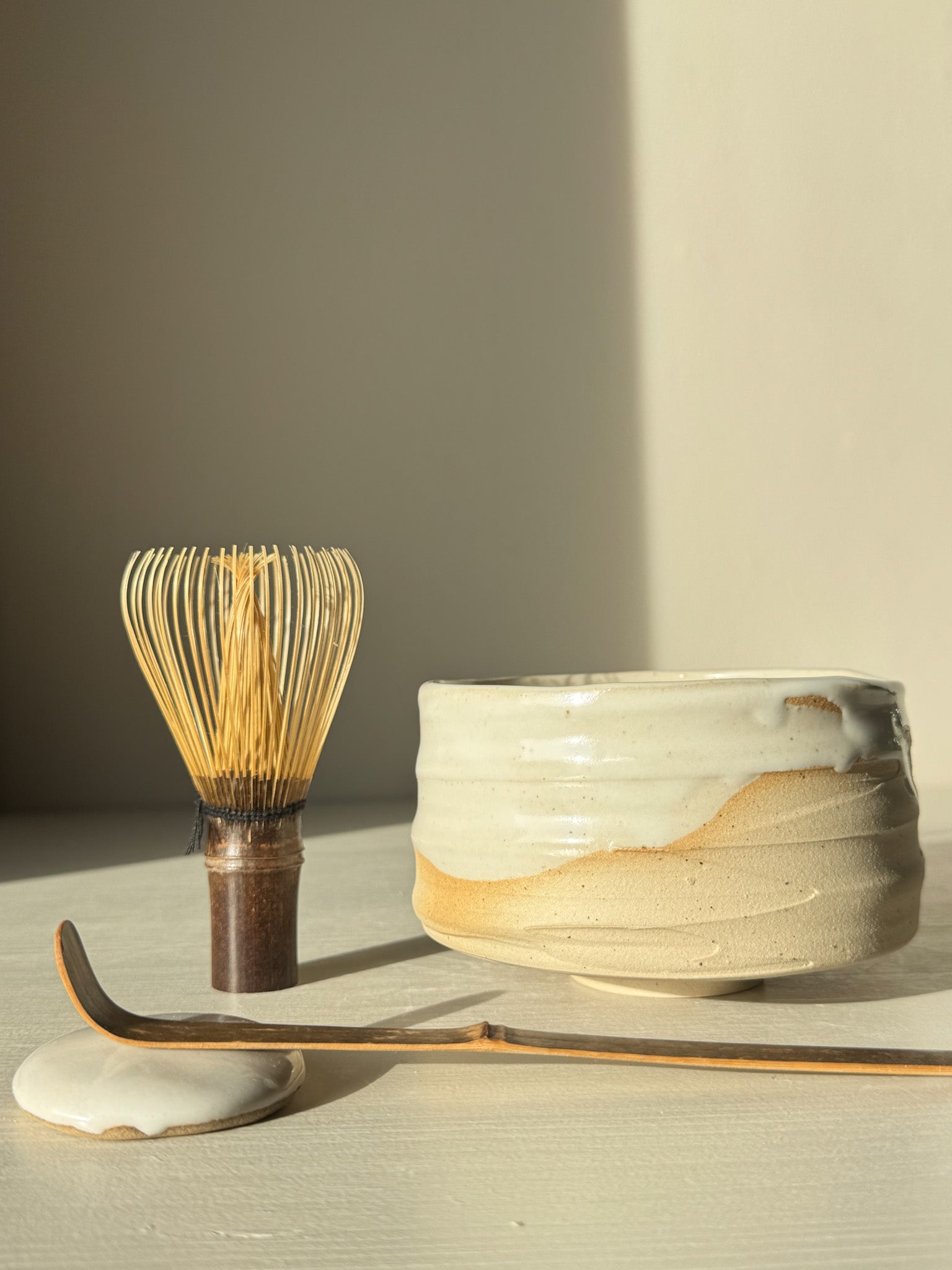 Matcha Bowl – Glossy White #05 with whisk and scoop, showcasing speckled stoneware clay and flowing white glaze.