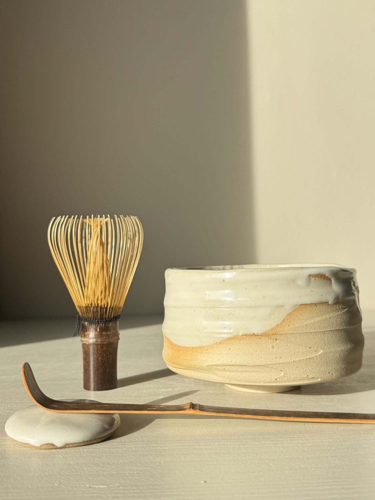 Matcha Bowl – Glossy White #05 with whisk and scoop, showcasing speckled stoneware clay and flowing white glaze.
