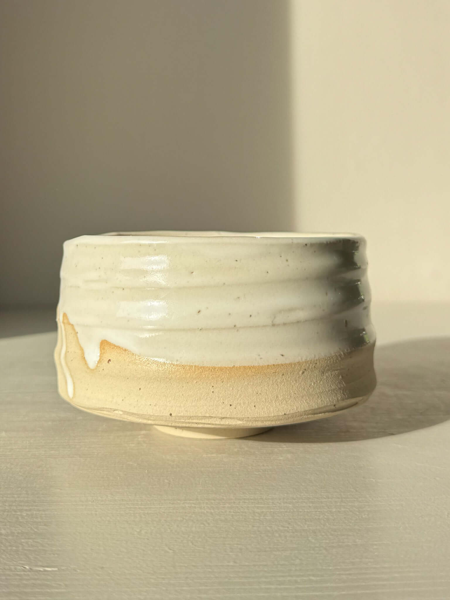 Matcha Bowl – Glossy White #05 made from speckled stoneware clay with a tactile surface, featuring glossy white glaze and exposed raw clay tones.