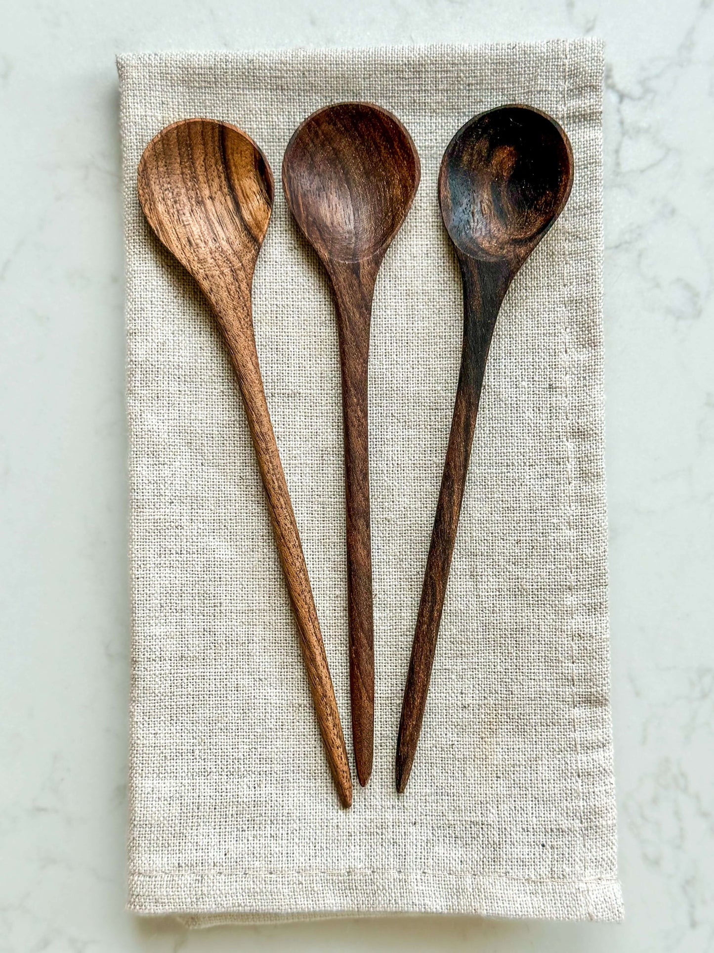 Set of three medium wooden spoons on linen cloth