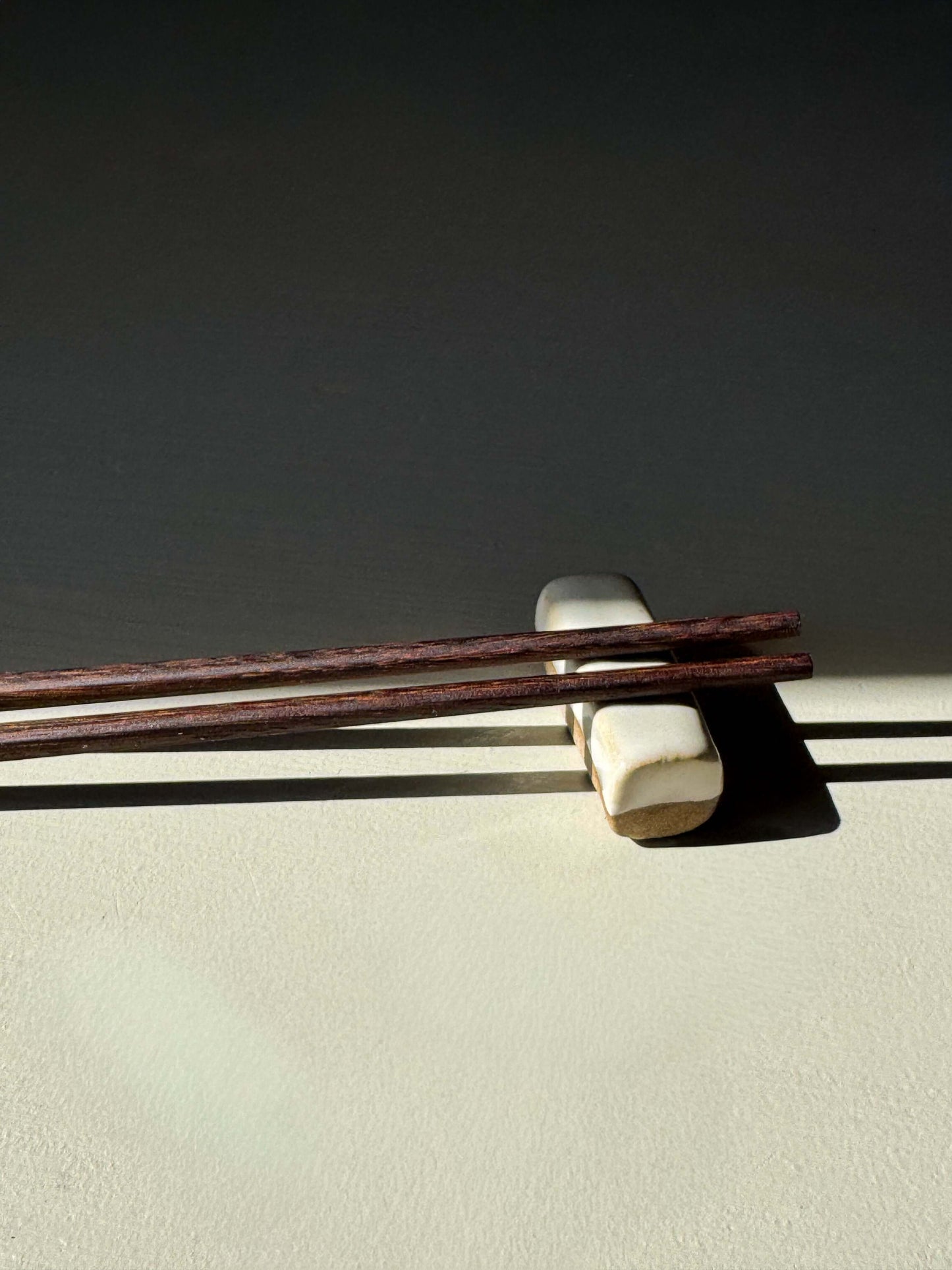 Wooden Chopsticks on ceramic holder, highlighting natural wood and handmade ceramic aesthetics.