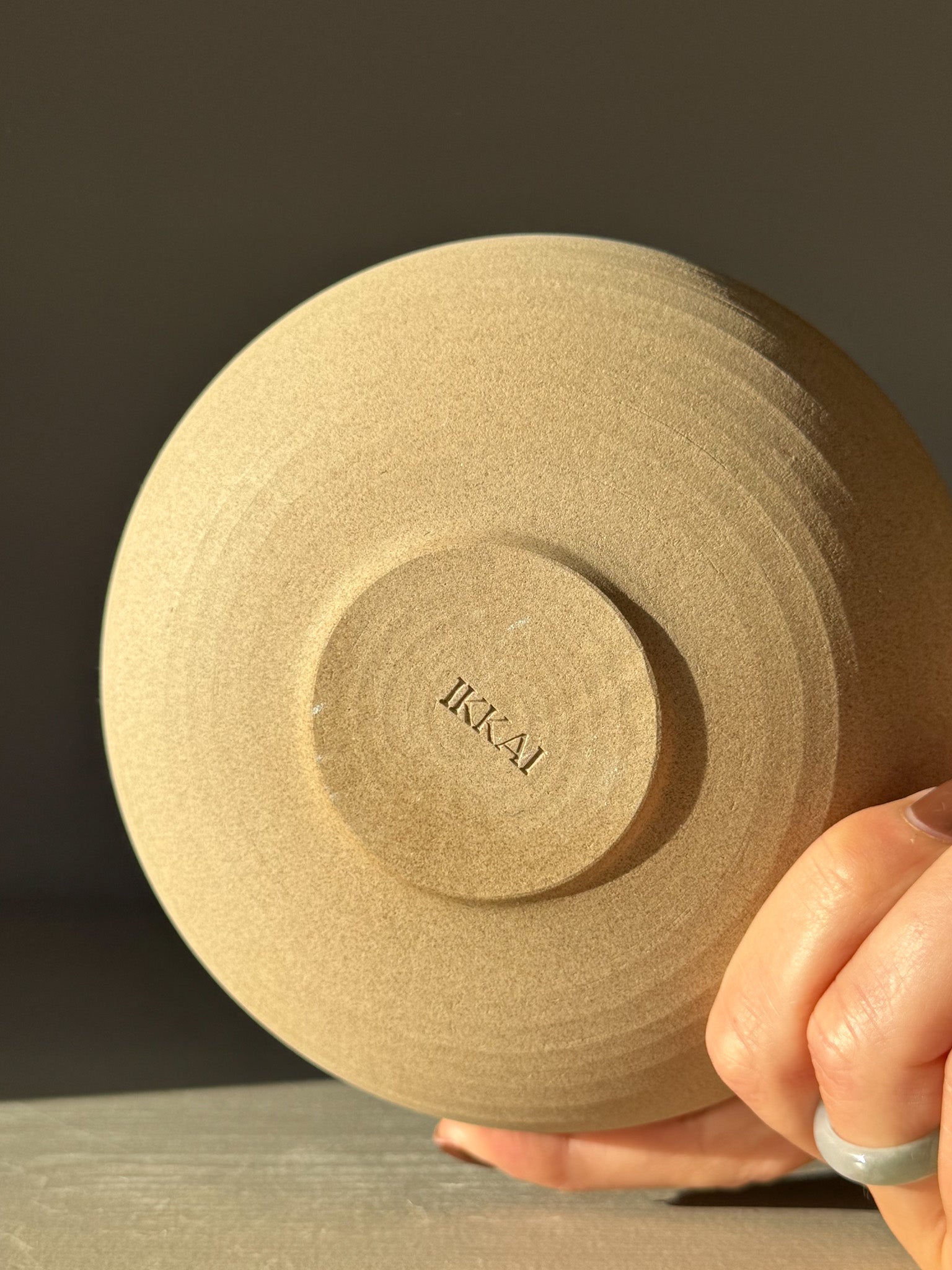 Underside view of Double-Walled Bowl - Inyo #03 with raw toffee-toned clay, showing circular throwing lines and artisan mark 'IKAI'