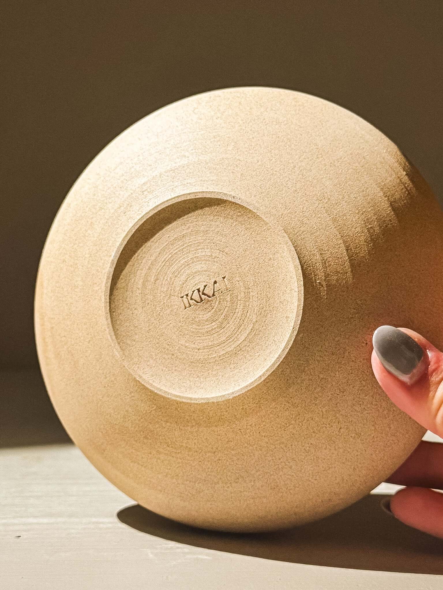Bottom view of a handmade double-walled stoneware bowl from the Inyo Series, displaying natural toffee-toned clay and texture.