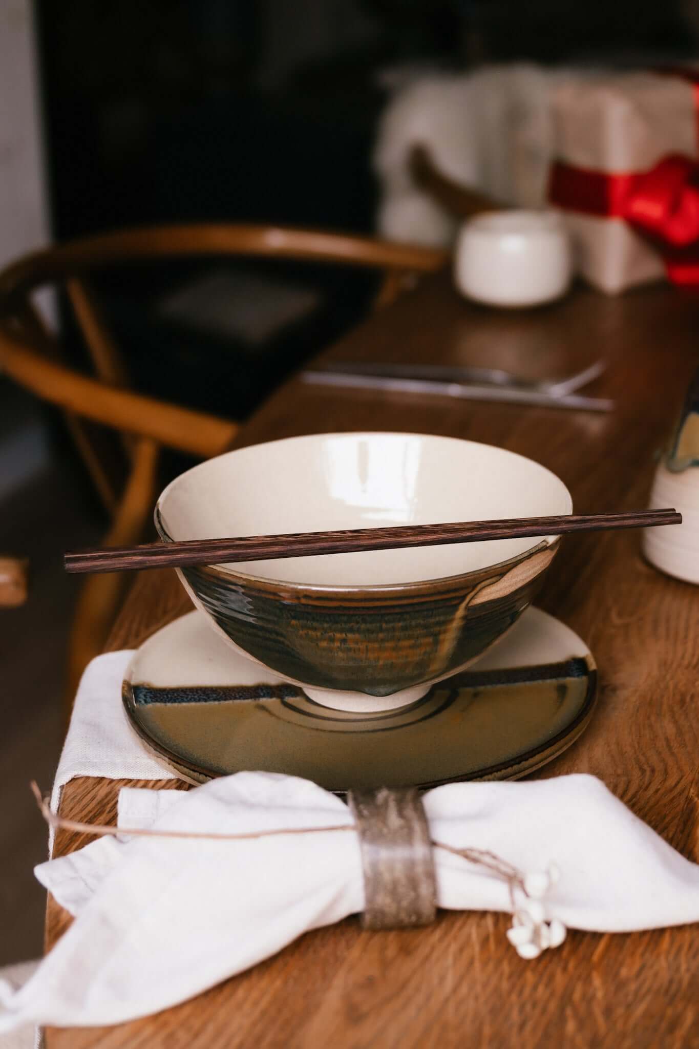 Table setting with Flat Round Breakfast Plate – Inyo, featuring handmade ceramic dishware with chopsticks on a wooden table.
