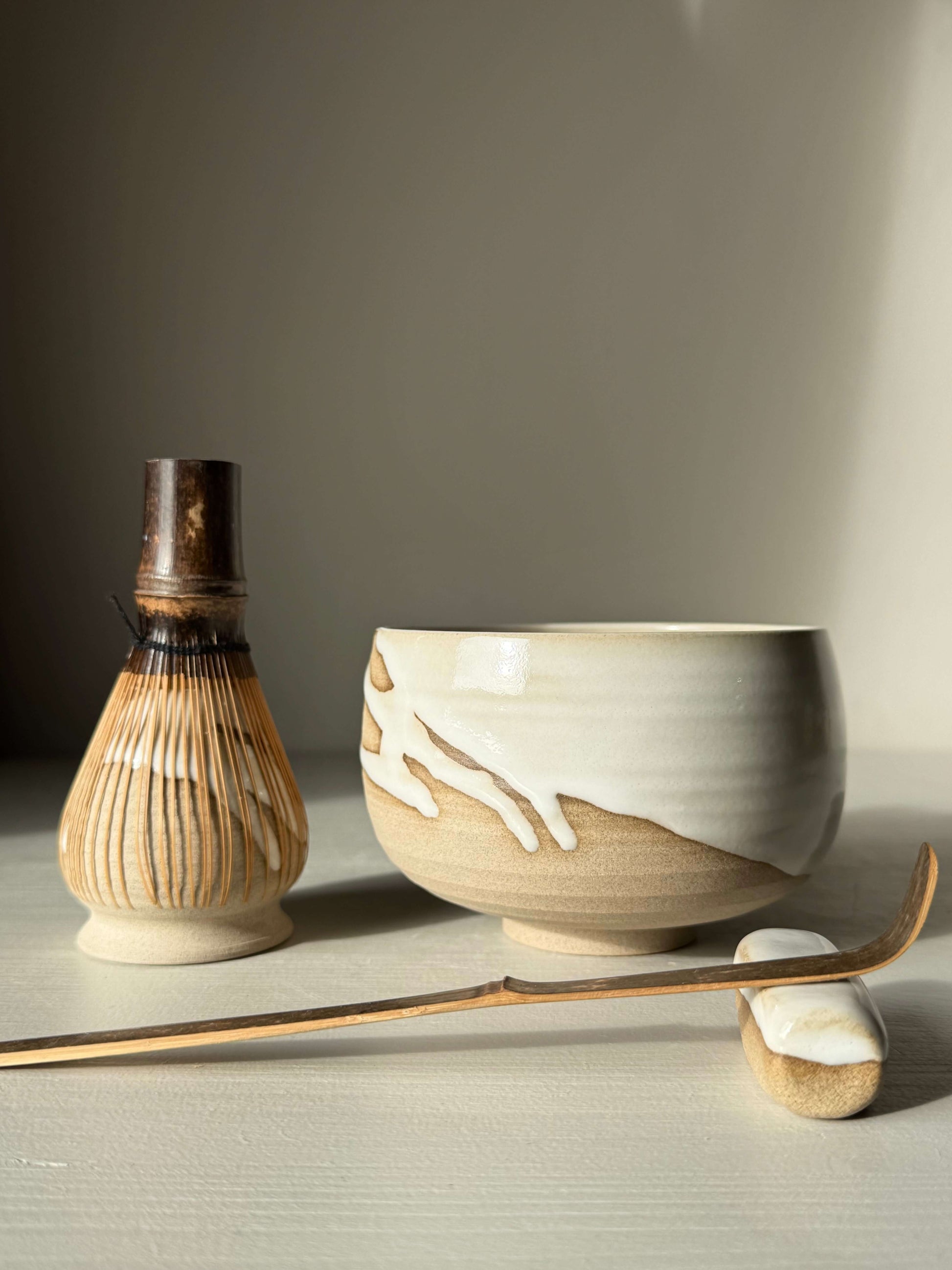 Matcha Bowl – Yuki #03 with handmade ceramic design, featuring toffee clay and glossy white glaze, alongside traditional tea tools.