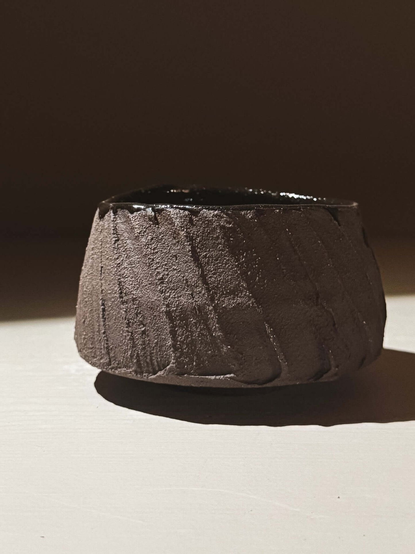 Yunomi Cup - Kuro #02 with textured dark brown clay and glossy dark glaze, showcasing earthy tones and volcanic stone inspiration.