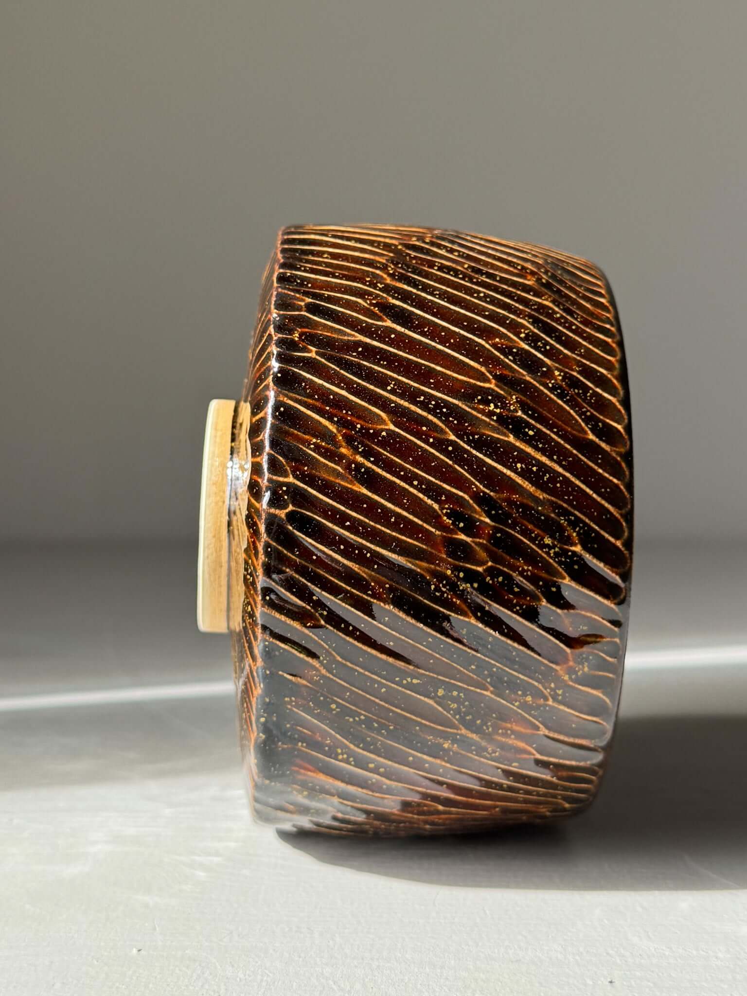 Handmade ceramic Matcha Bowl – Kinsei #05 with glossy brown exterior and gold spiral design, showcasing unique craftsmanship.