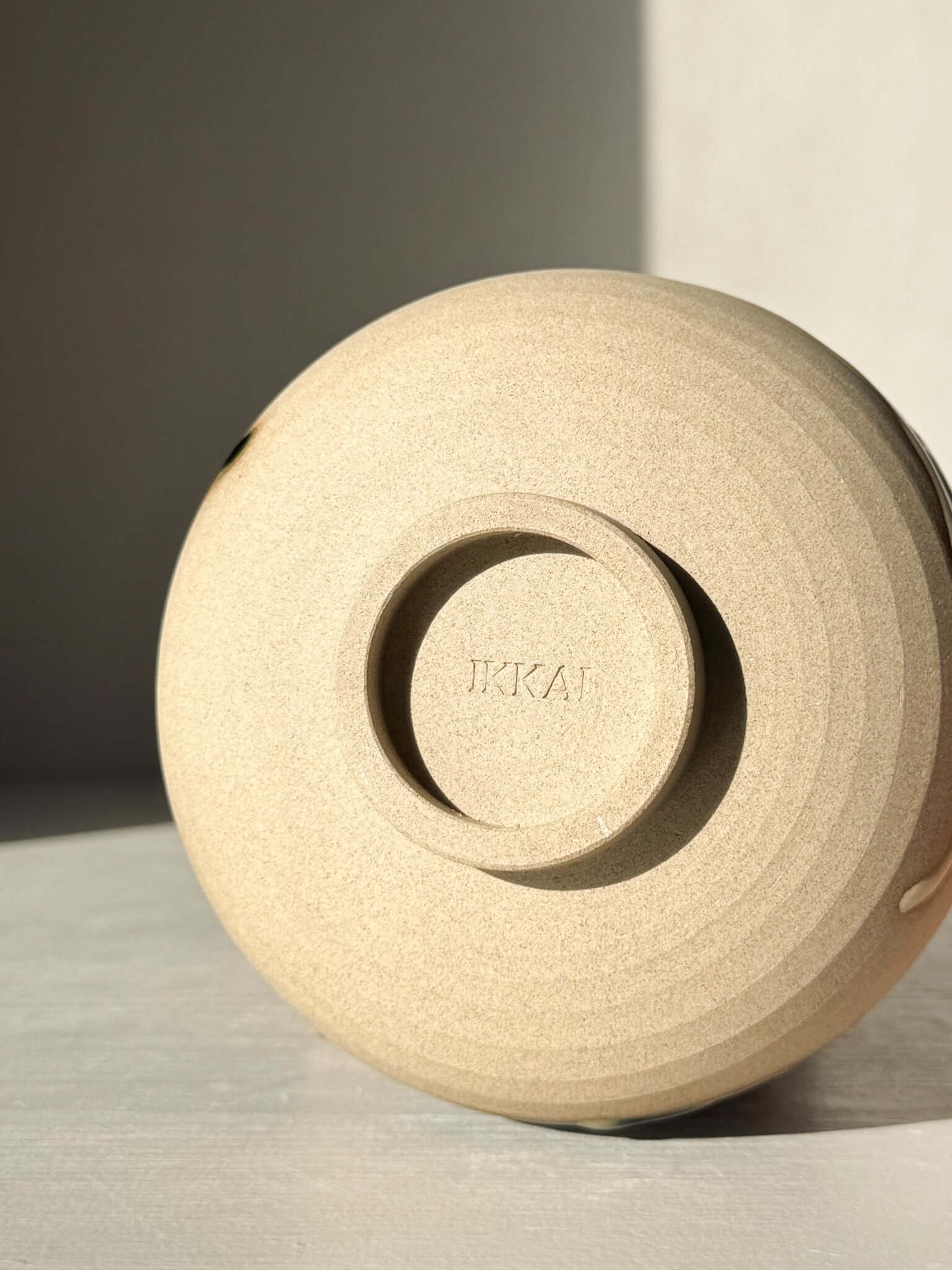 Bottom view of a handmade ceramic Matcha Bowl – Mori #01, displaying its natural stoneware texture and IKAI branding.