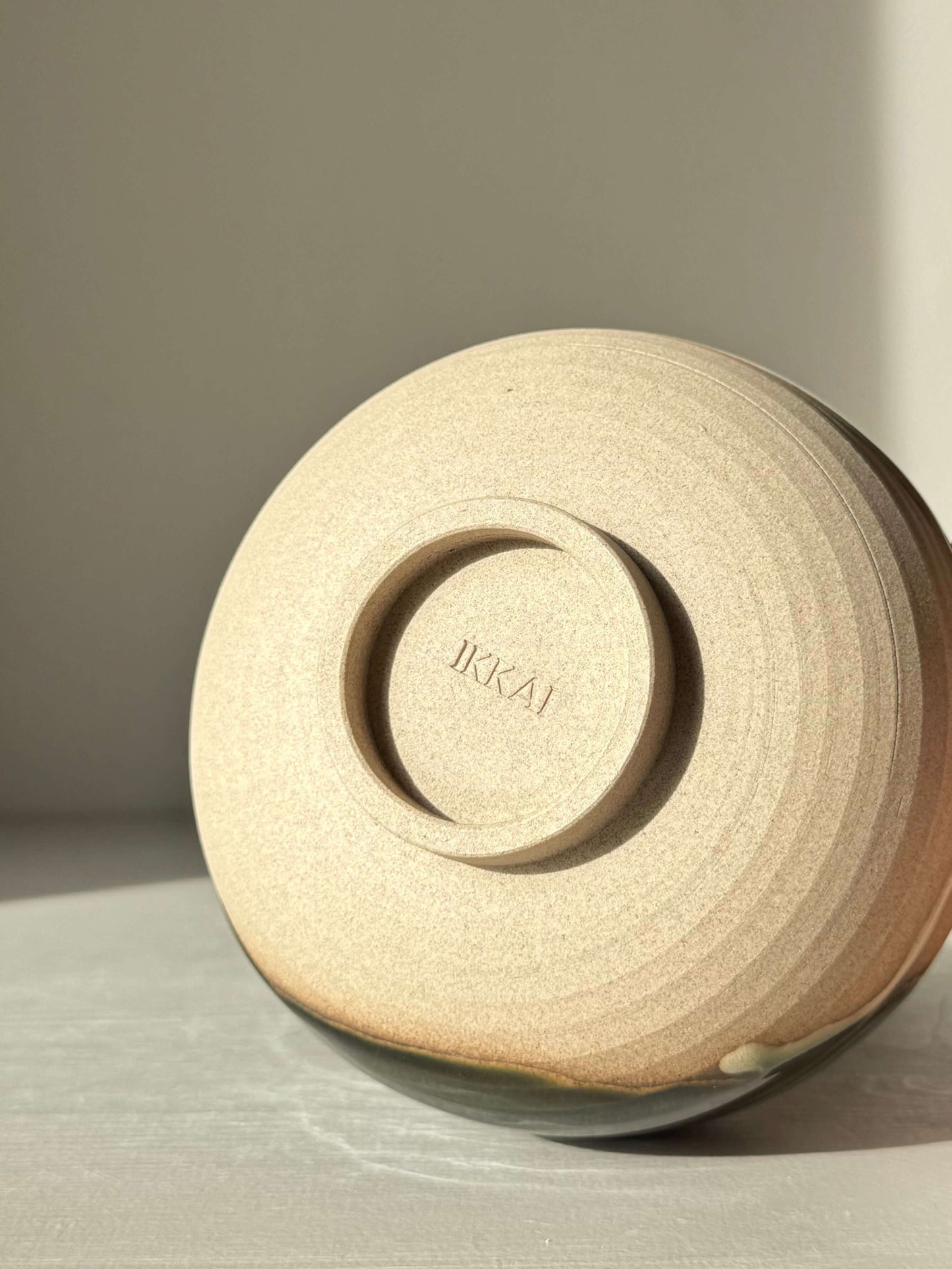 Base view of a handmade ceramic Matcha Bowl with Spout – Mori #06, showing natural stoneware and layered green and brown glazes.