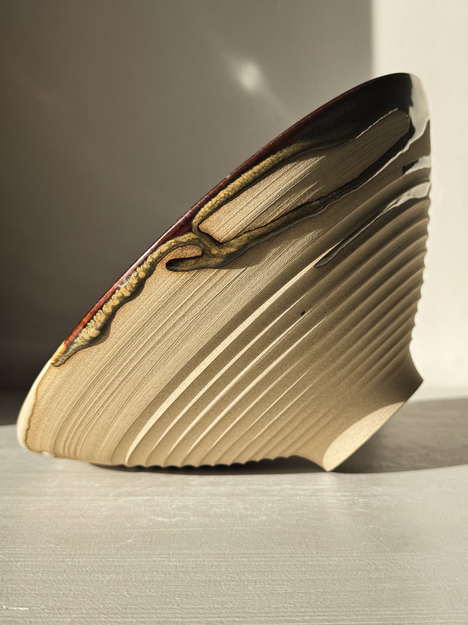 Side view of Medium Carved Bowl - Inyo #02 with sculptural carved exterior and flowing glaze drips.