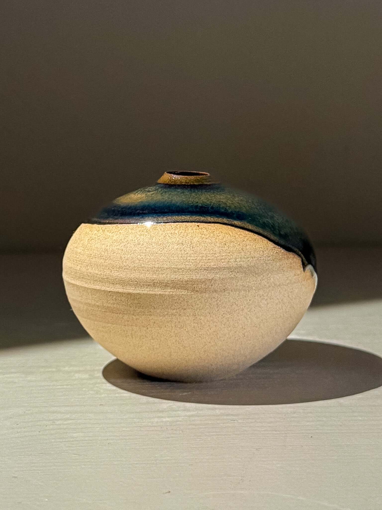Handmade ceramics Orb Vase – Tenmoku #14, showcasing a smooth rounded shape and unique glaze patterns.