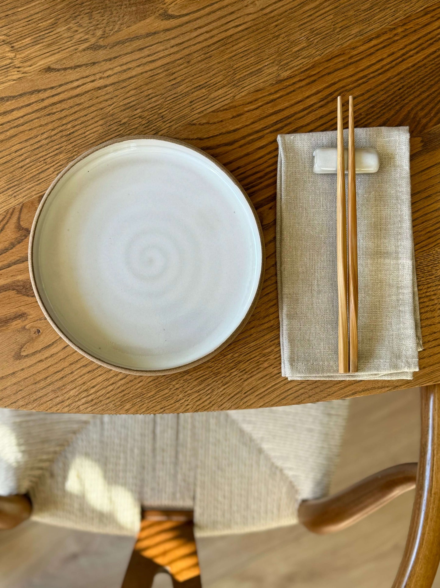 Plate – Yuki Series handmade ceramic with white glaze and toffee clay, shown resting on a wooden table beside a napkin and chopsticks.