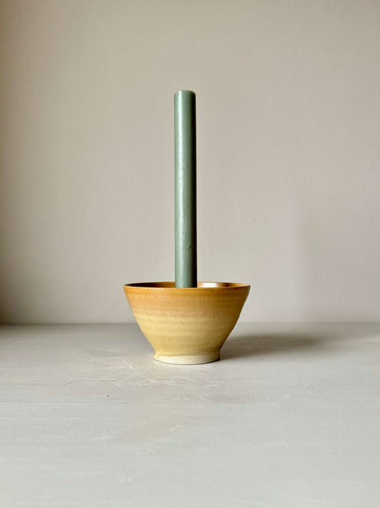 Handmade golden yellow candlestick holder in stoneware with green candle; unique wheel-thrown design, 8cm high and 14.5cm in diameter.