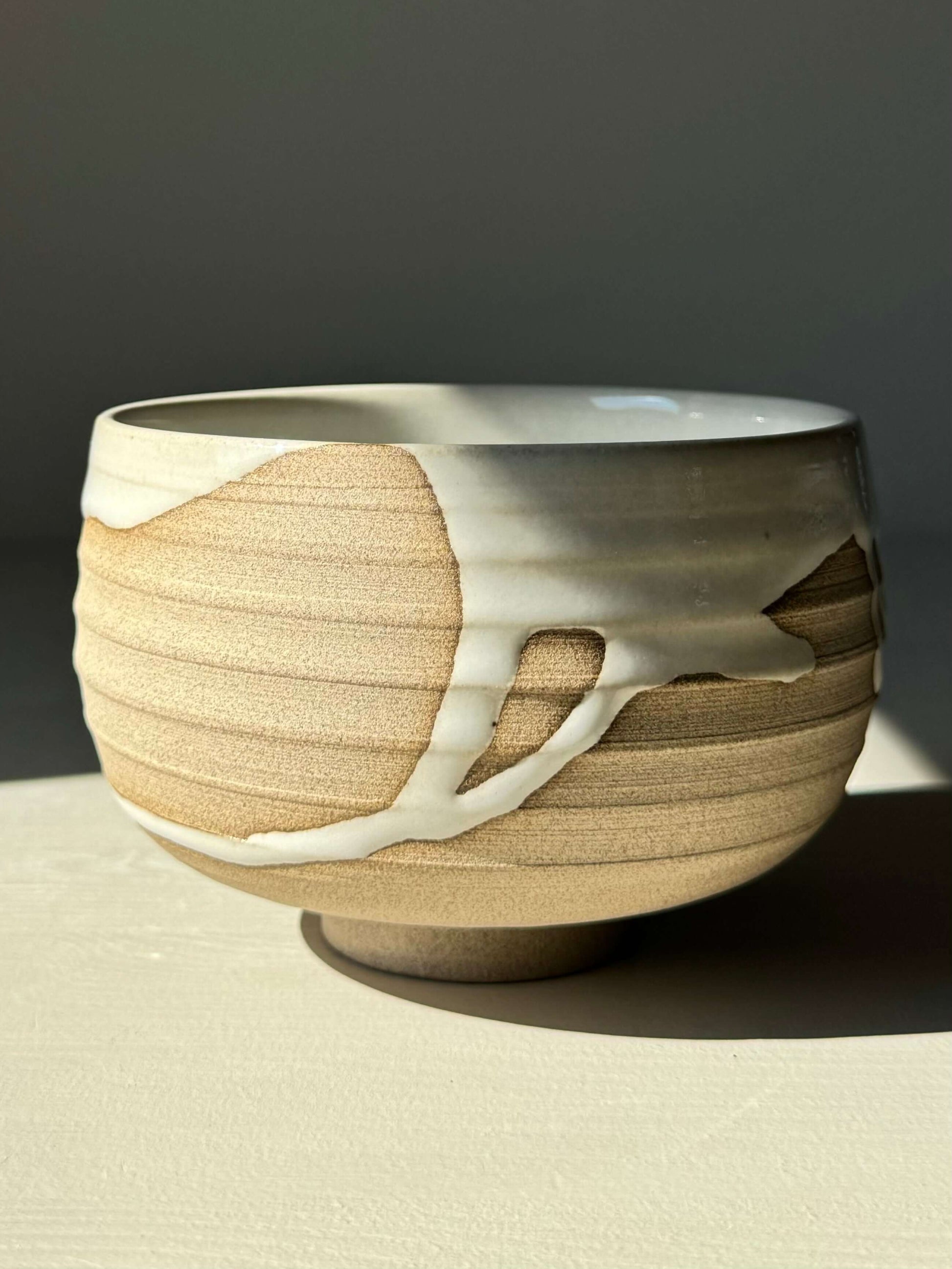 Handmade Matcha bowl from Yuki Series #07 with toffee clay and white glaze, showcasing unique drips and a grounding design.