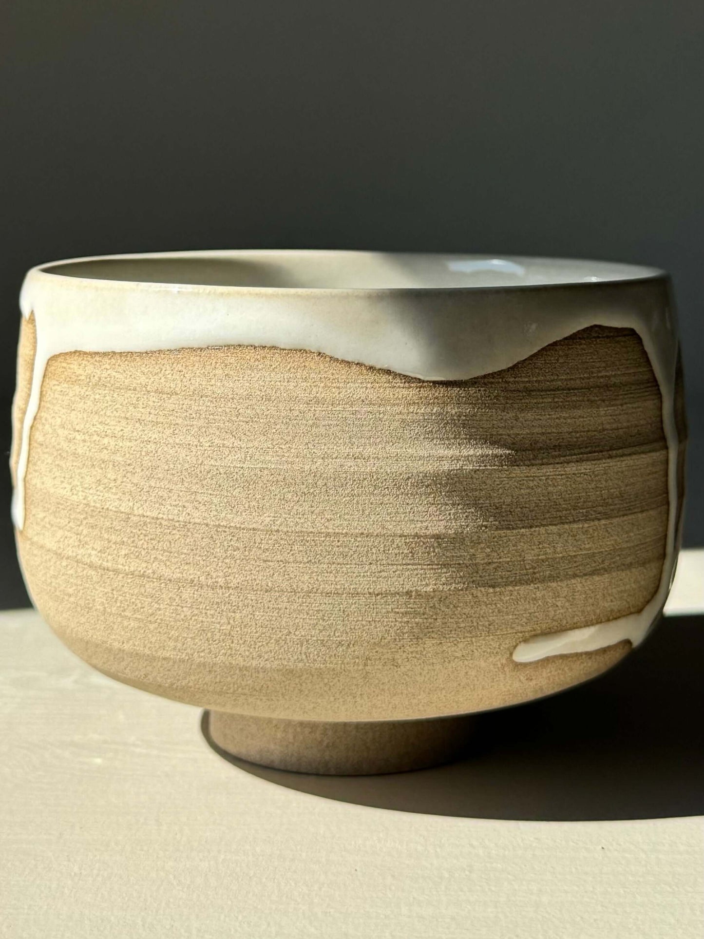 Handmade Matcha bowl from Yuki Series #09 with toffee clay base and glossy white glaze, featuring unique drip pattern.